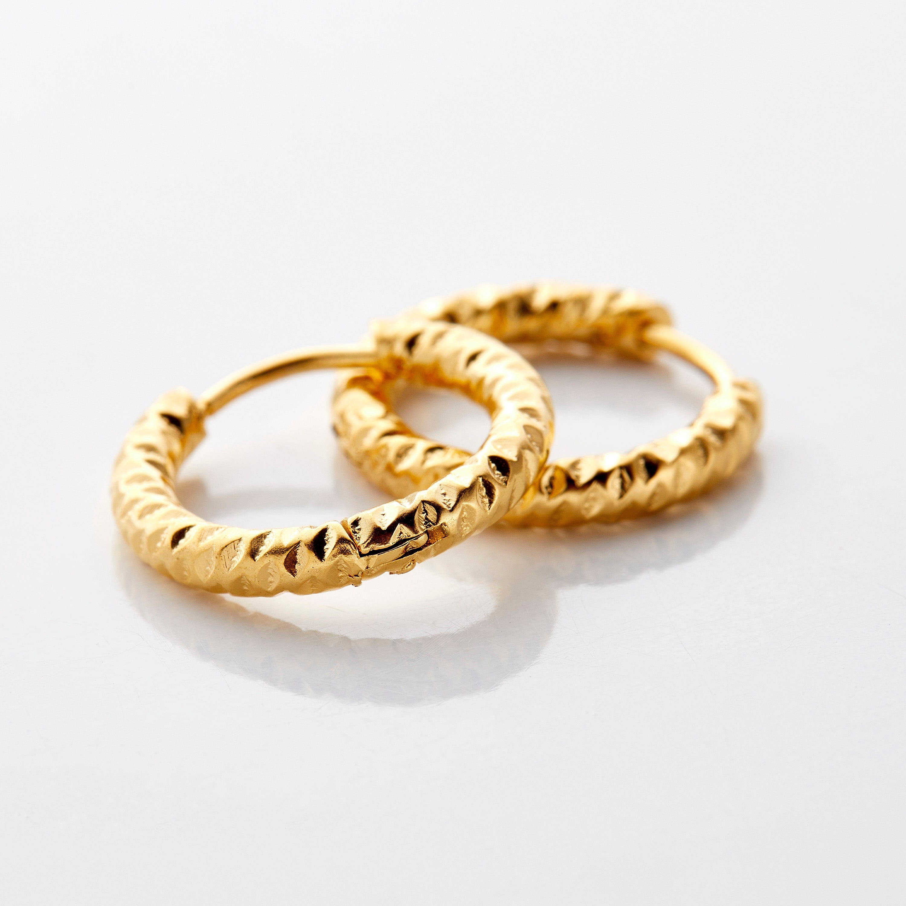 Mini gold hoop earrings for sensitive ears, showcasing the unique imperfect edges.
