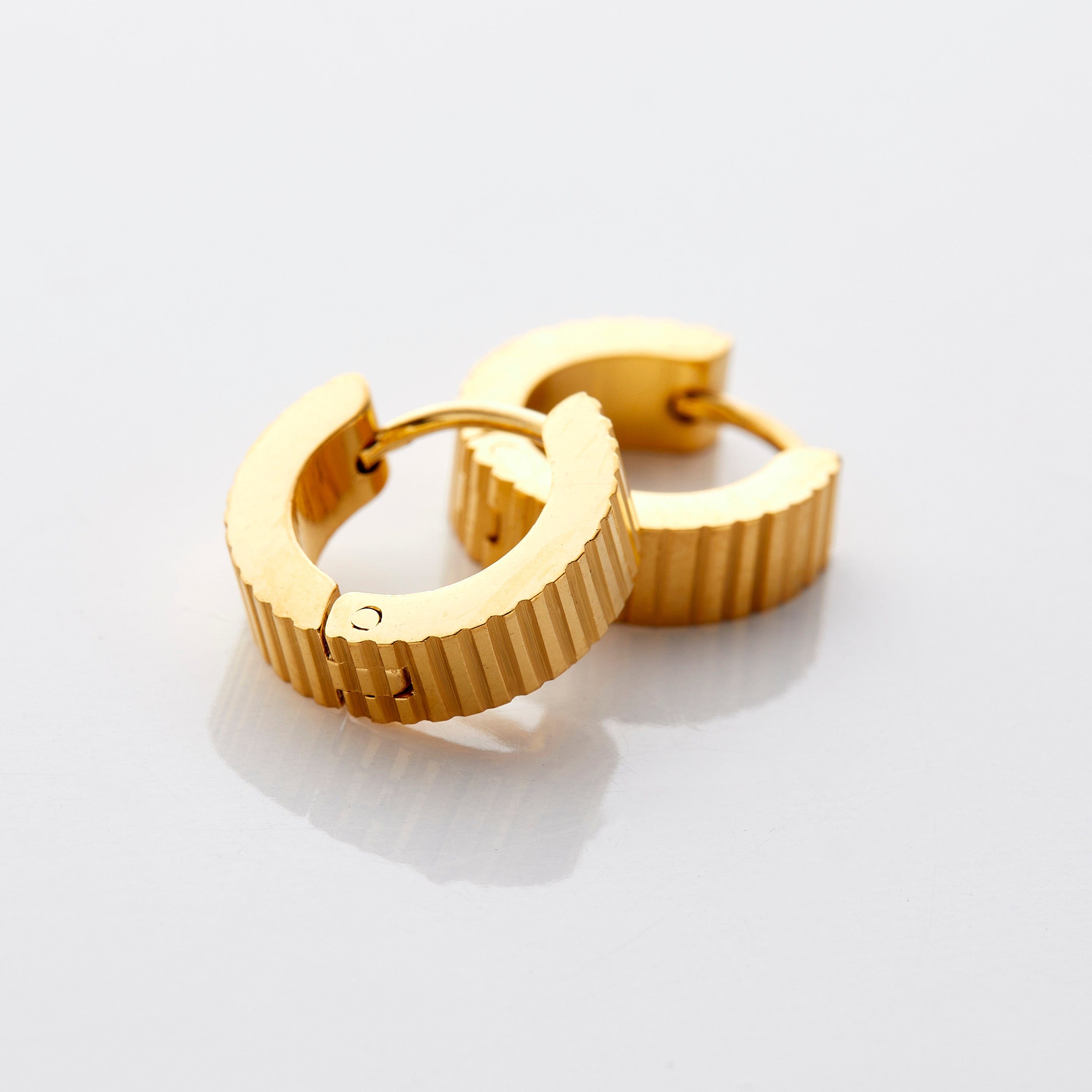 Elegant ridged gold hoop earrings on a model, showcasing a stylish look.