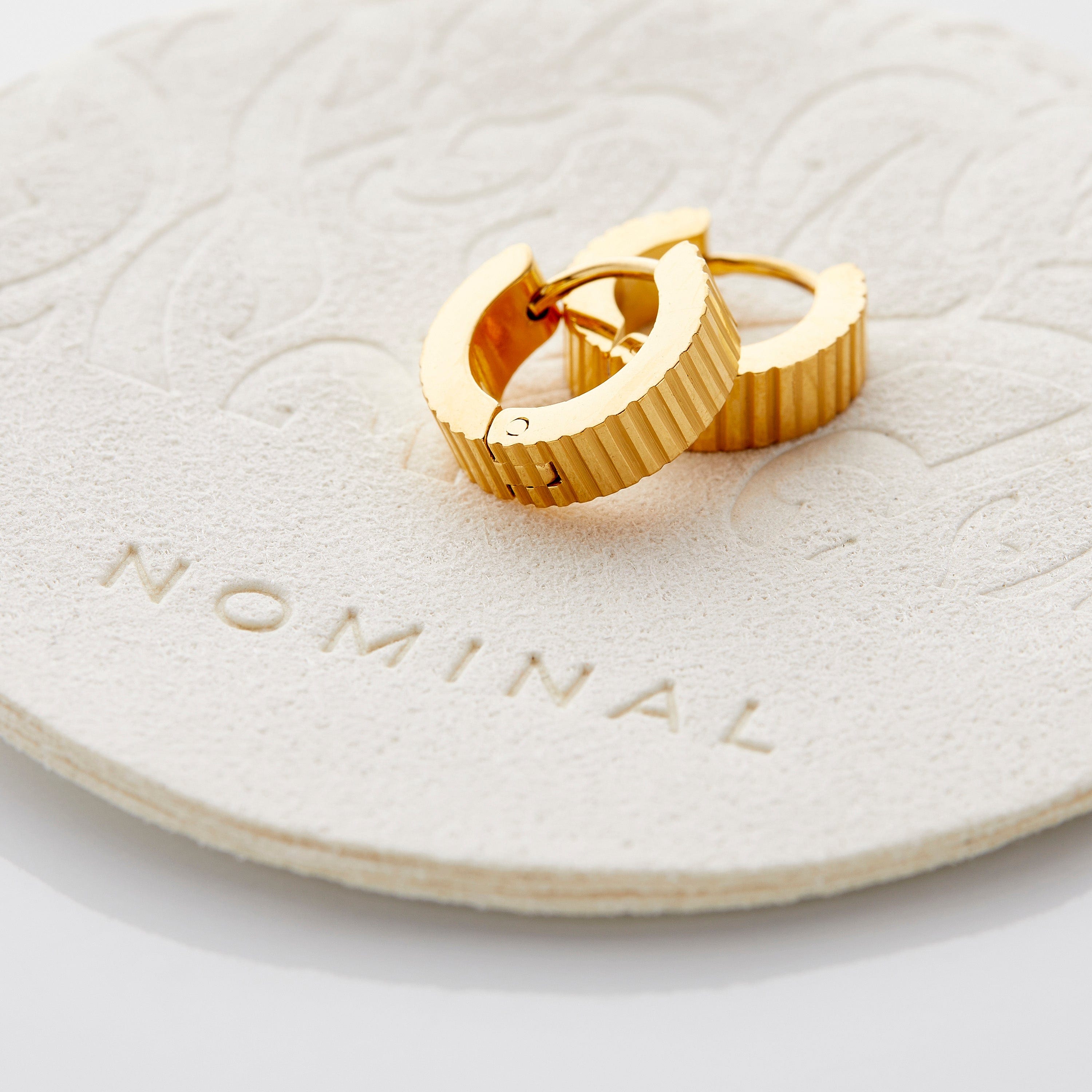 Elegant ridged gold hoop earrings on a model, showcasing a stylish look.