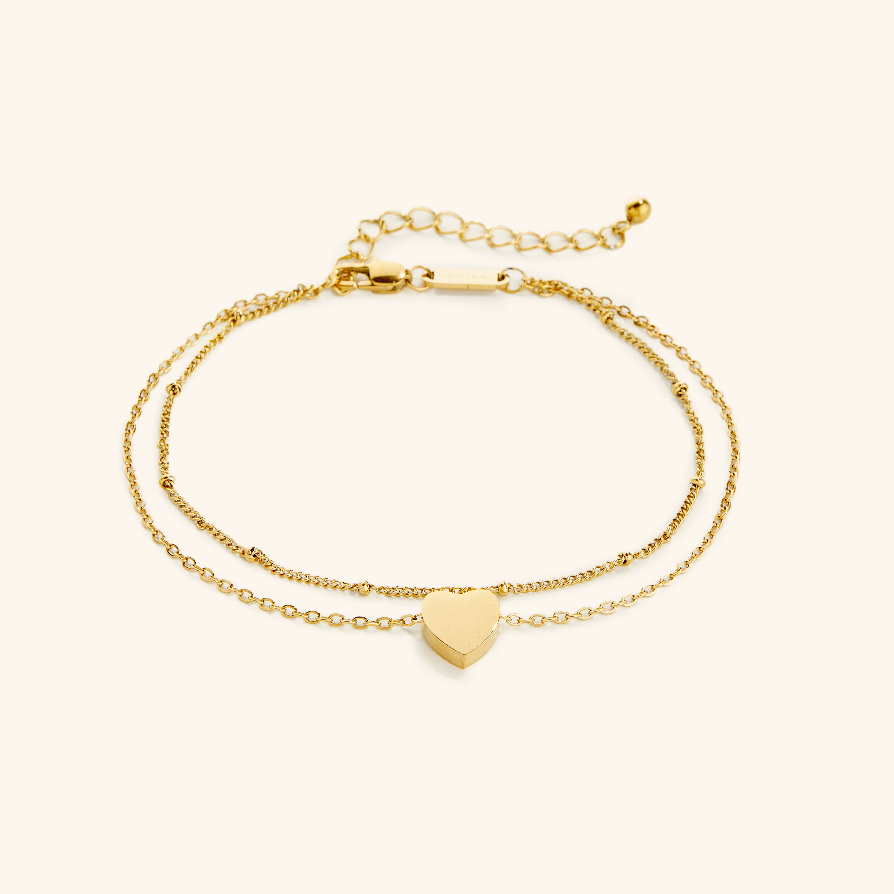 Charming heart layered gold anklet displayed on a soft velvet pouch, showcasing its intricate design.