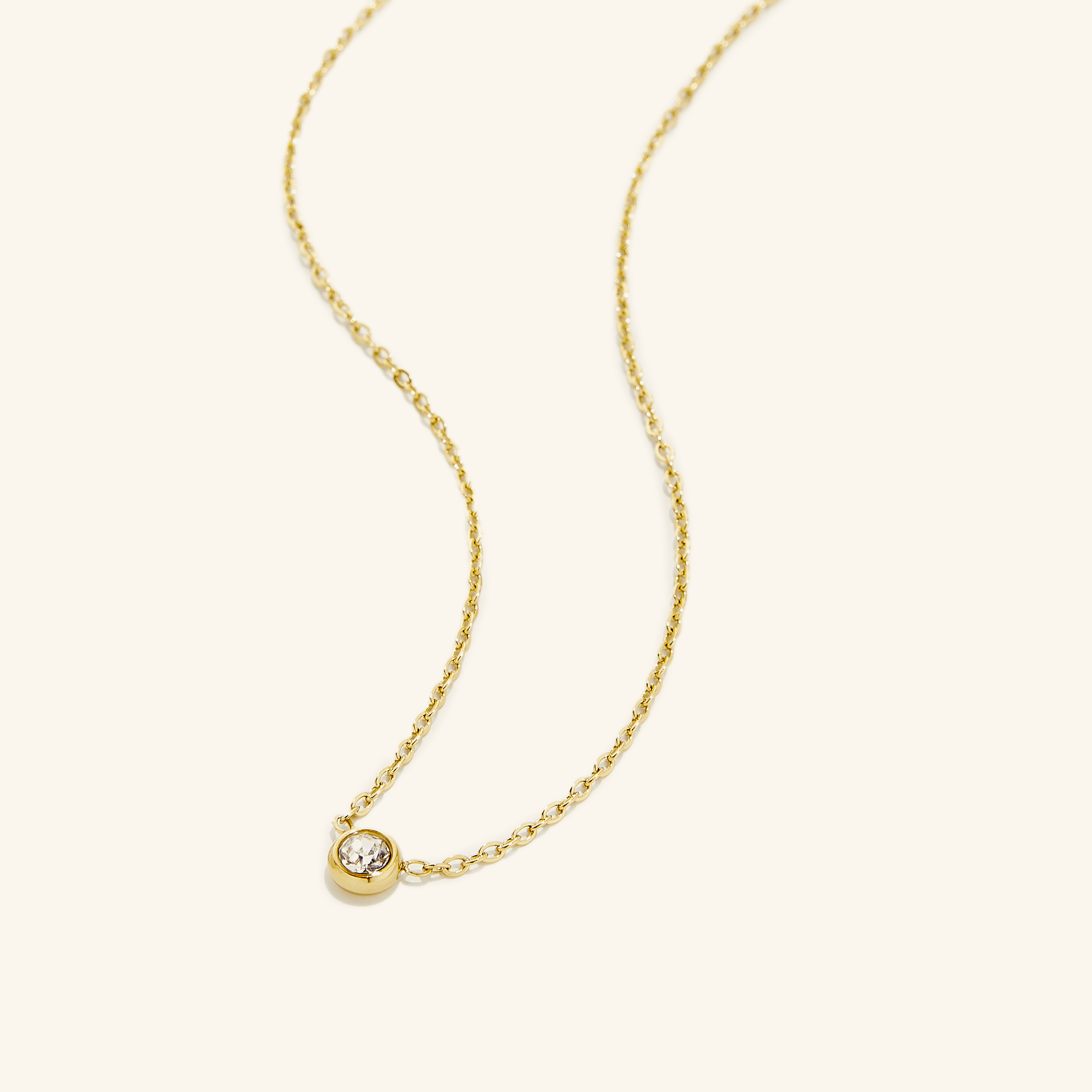 Radiant gold bezel gemstone necklace displayed on a model, showcasing its shine and minimalist design.