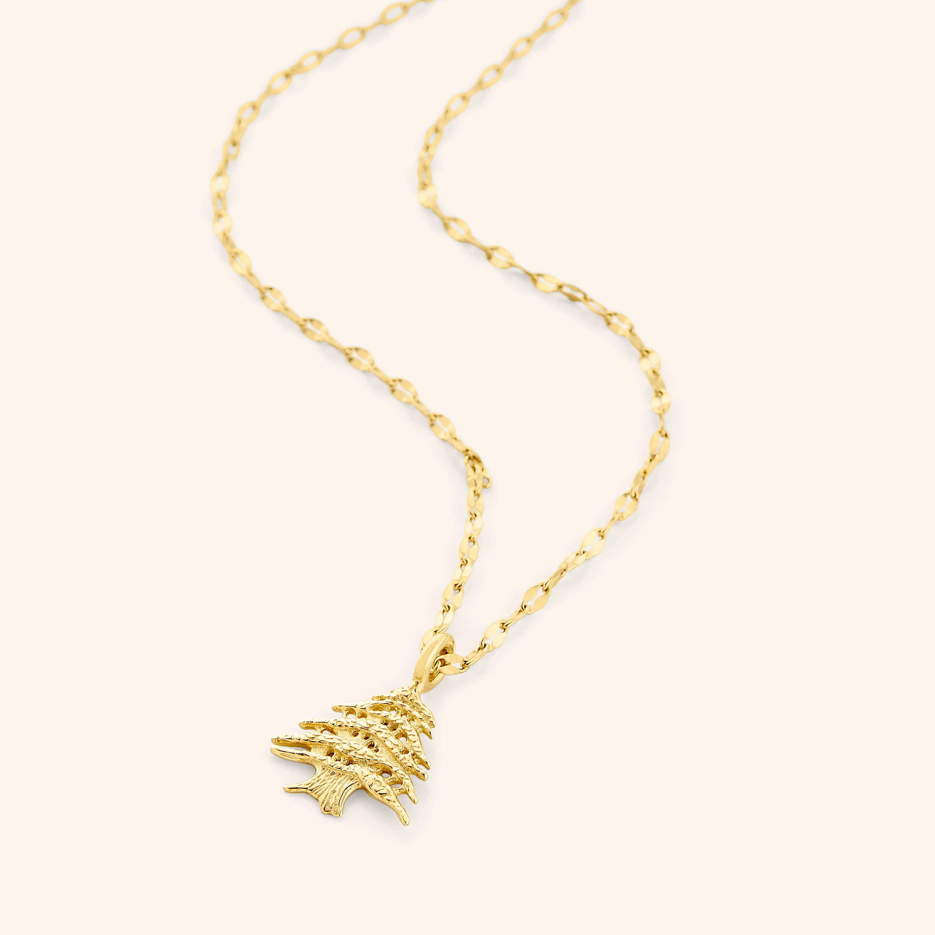 Cedar of Lebanon gold pendant necklace displayed on a velvet pouch.