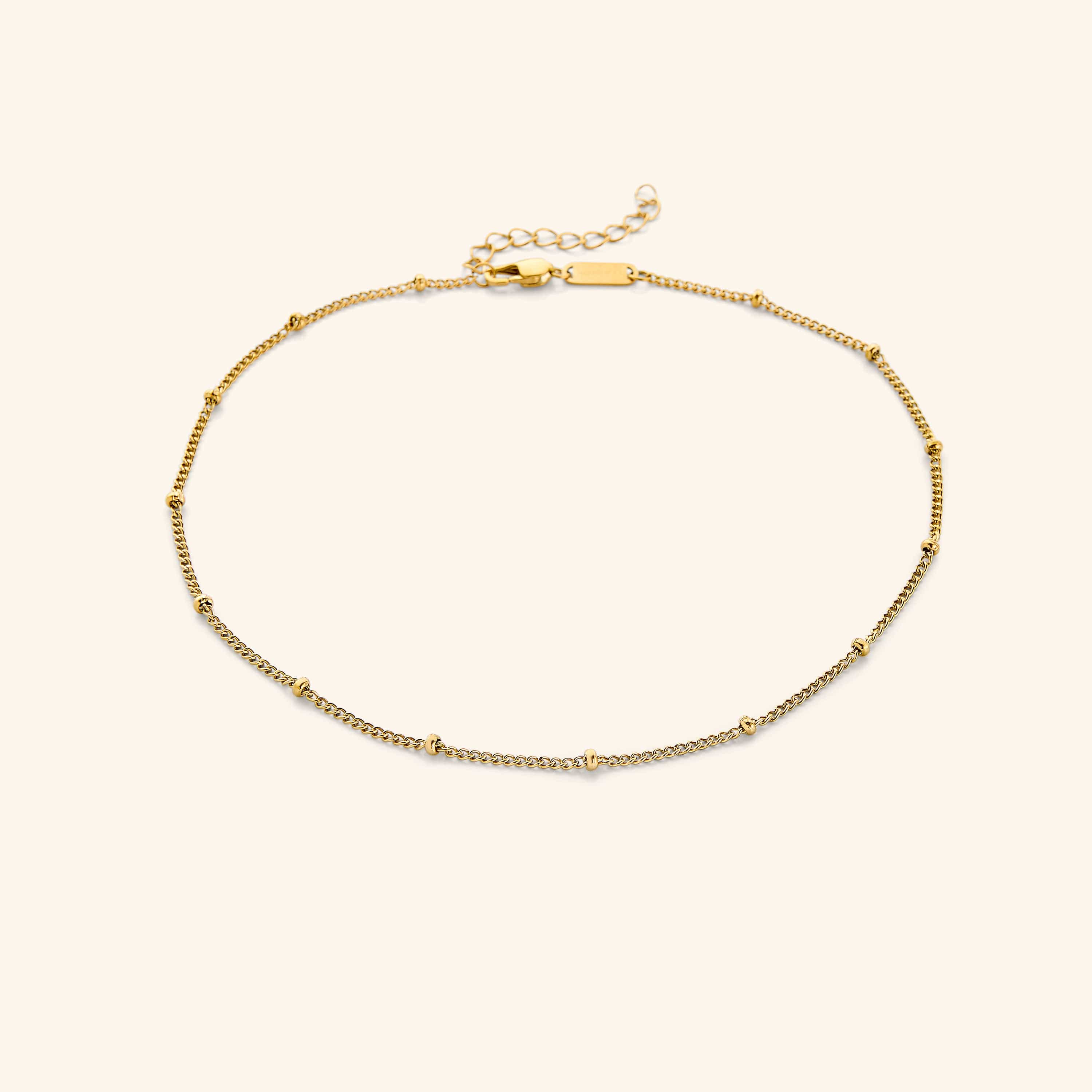 Elegant gold dotted chain choker displayed on a soft velvet background
