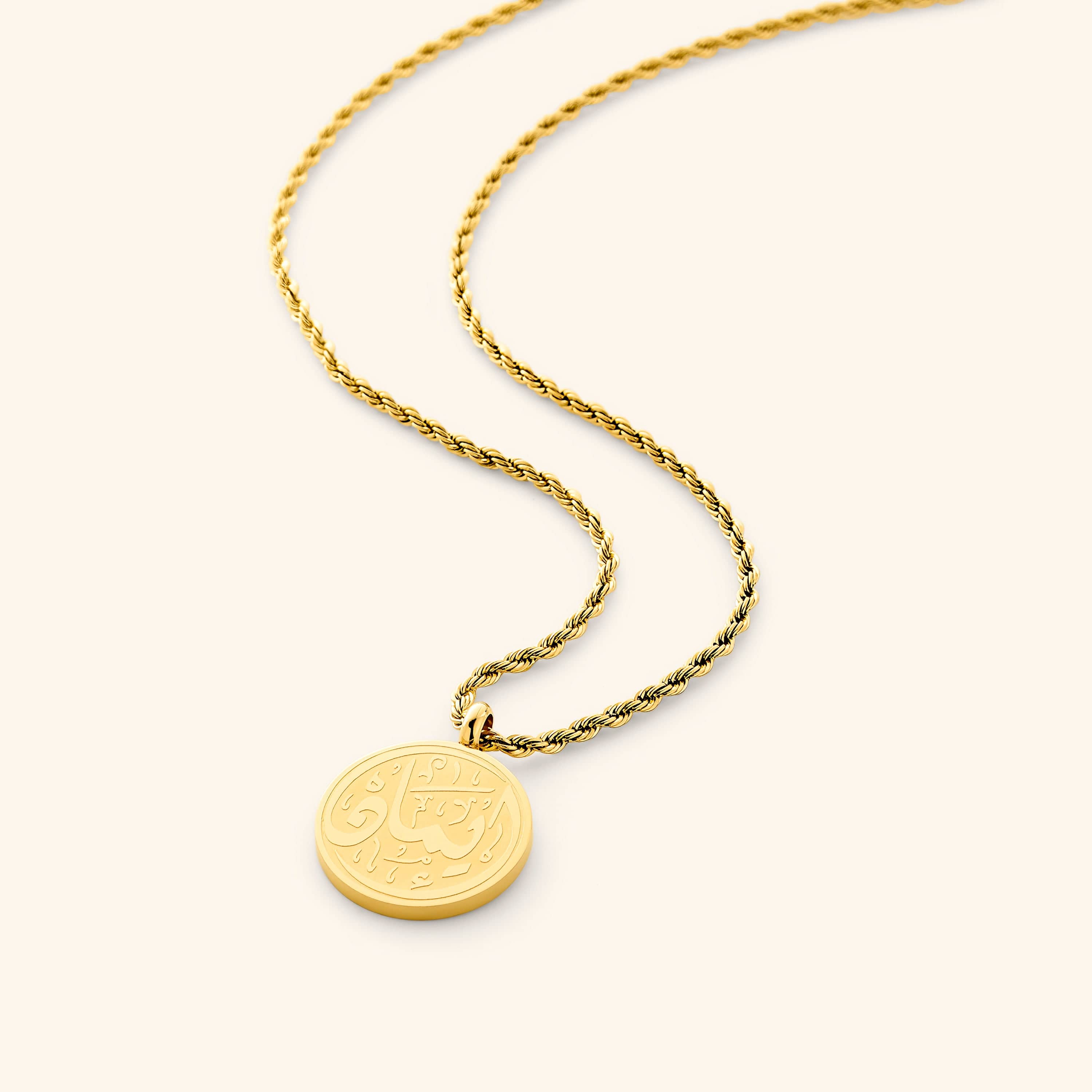 Close-up of the circular arabic pendant necklace engraved with 'Iman' on gold-plated surface