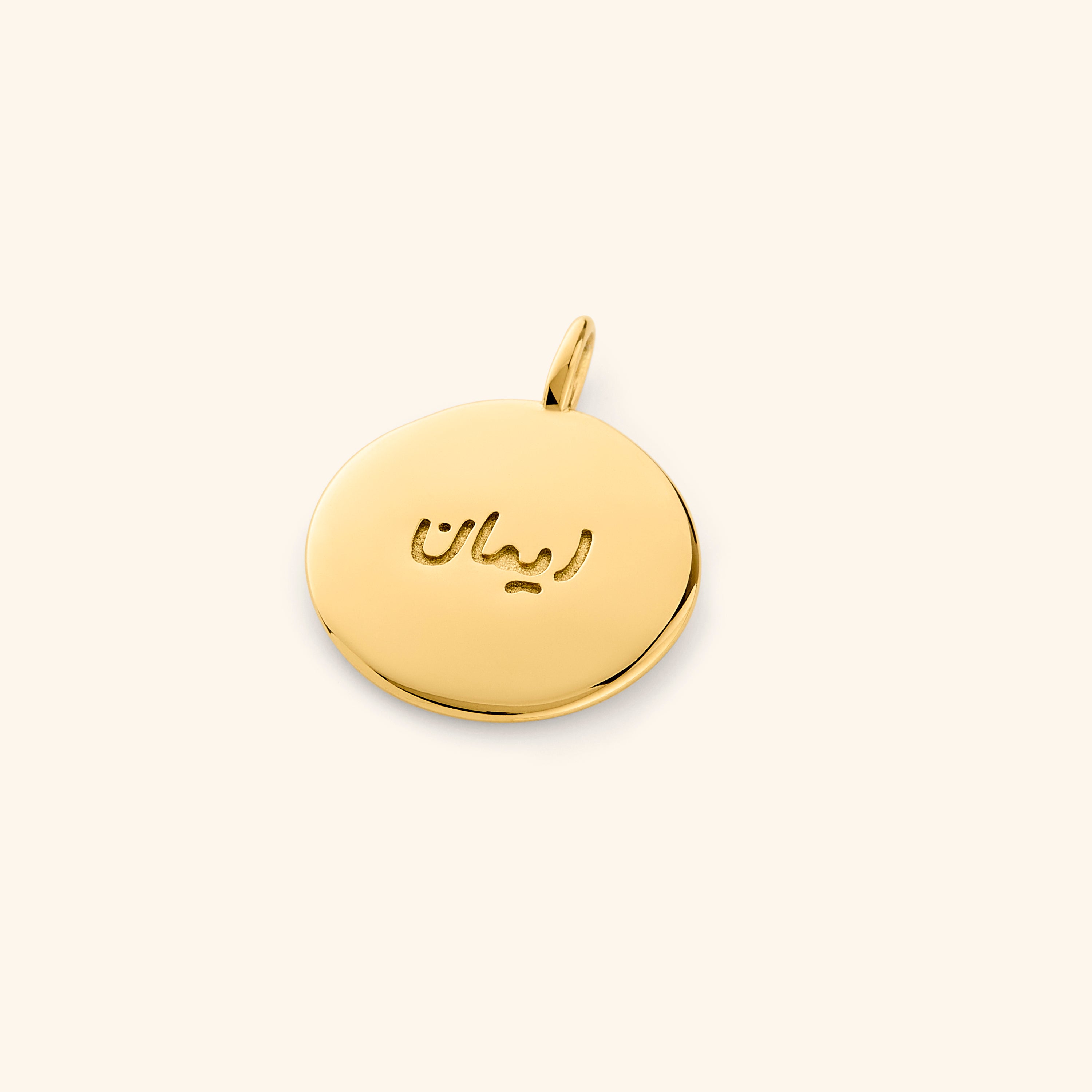 Close-up of the Iman Faith Charm highlighting its Arabic engraving and gold finish.