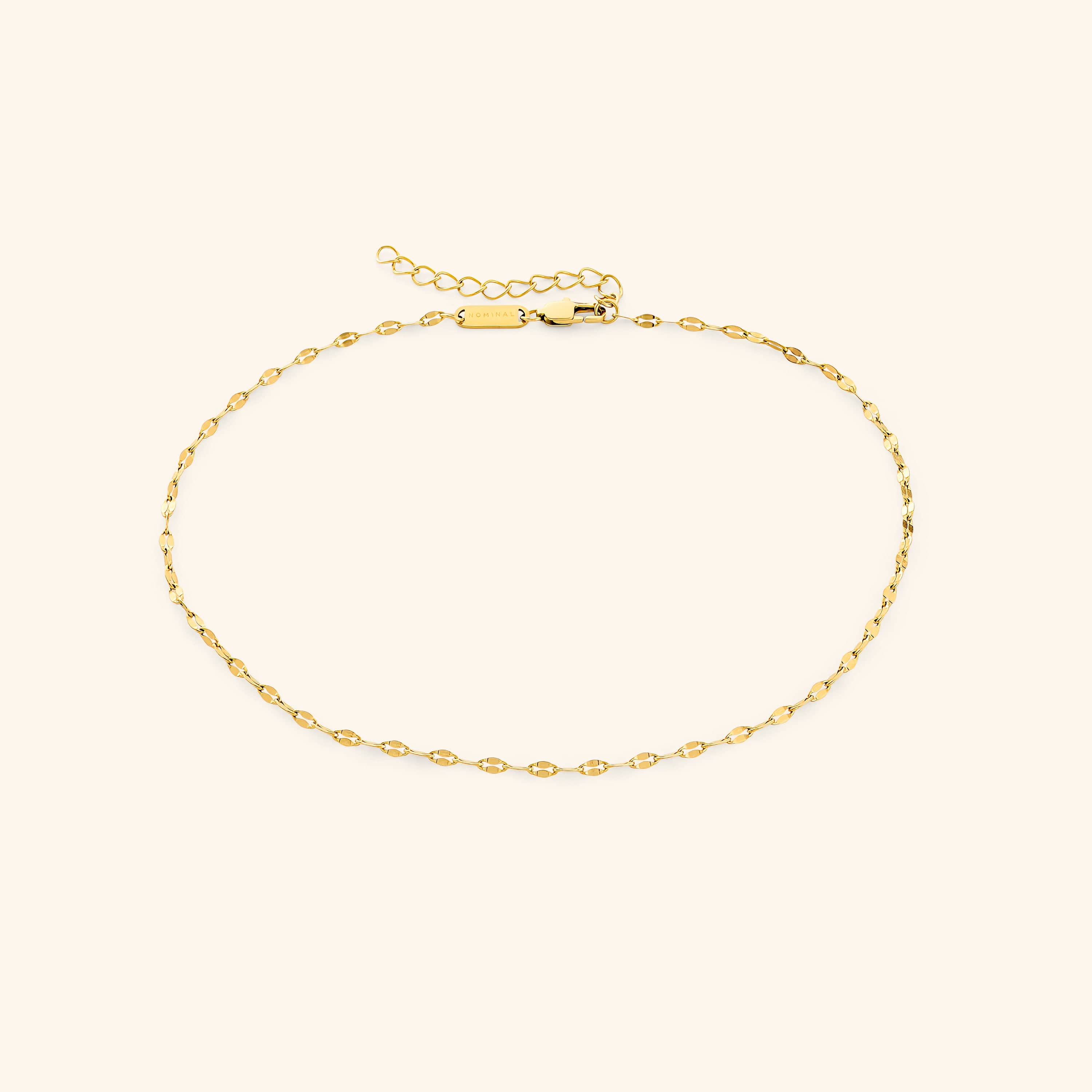 Elegant minimalist gold choker draped over a velvet surface, showcasing its delicate chain.