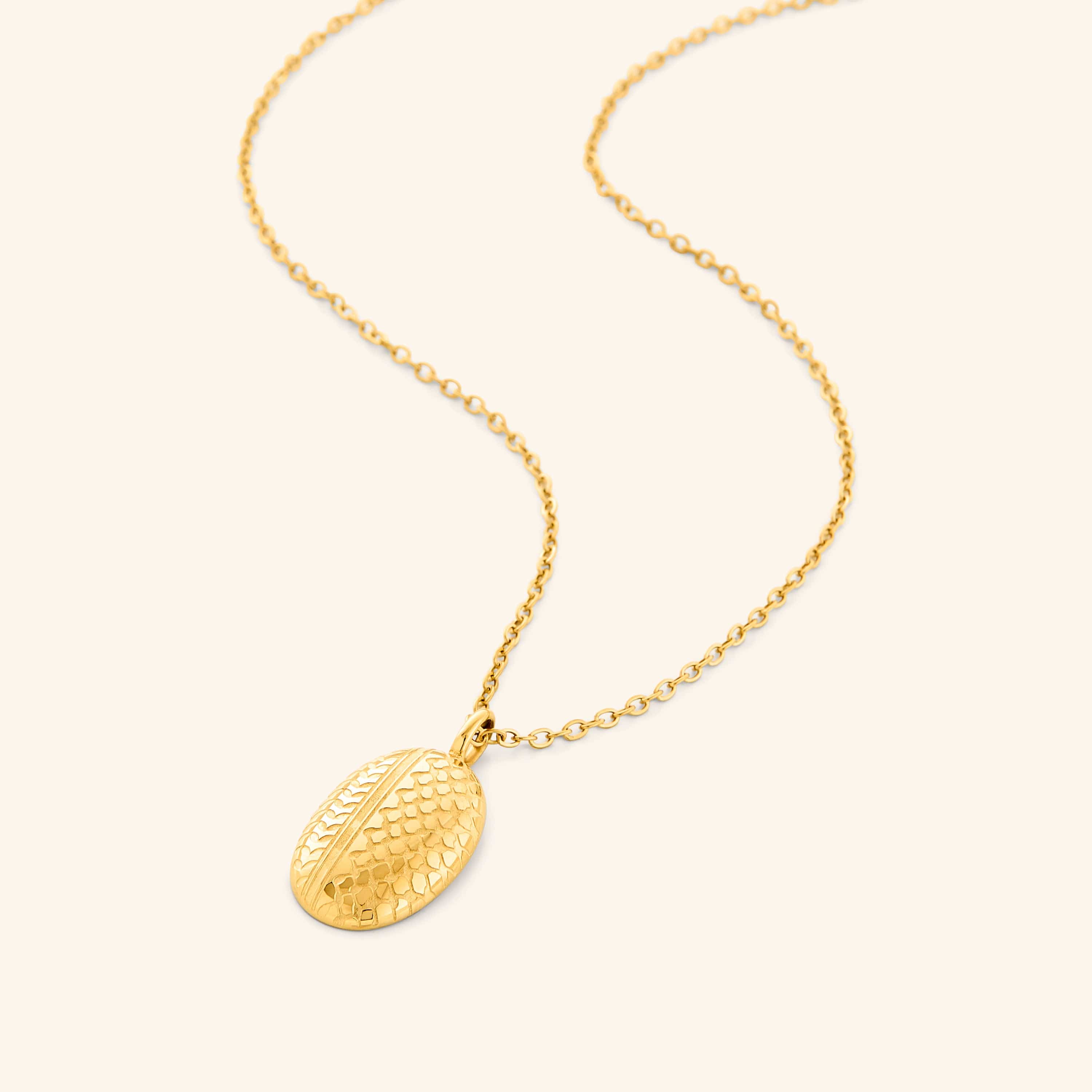 Close-up of gold-plated keffiyeh necklace pendant highlighting olive leaf motif