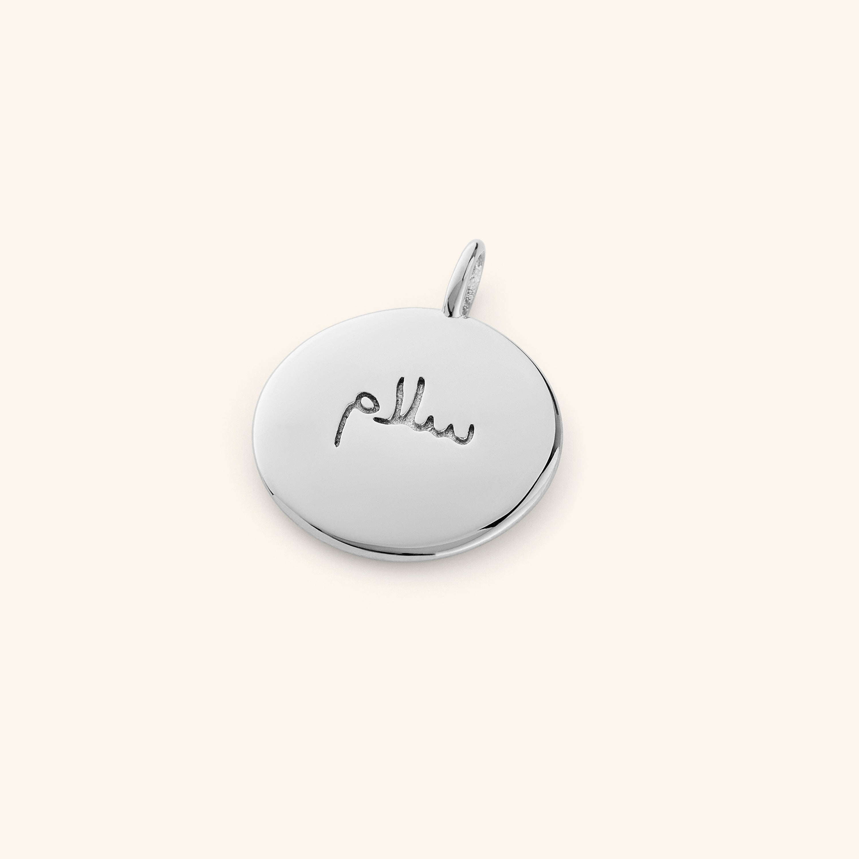 Gold charm stacked with other elegant jewelry pieces.