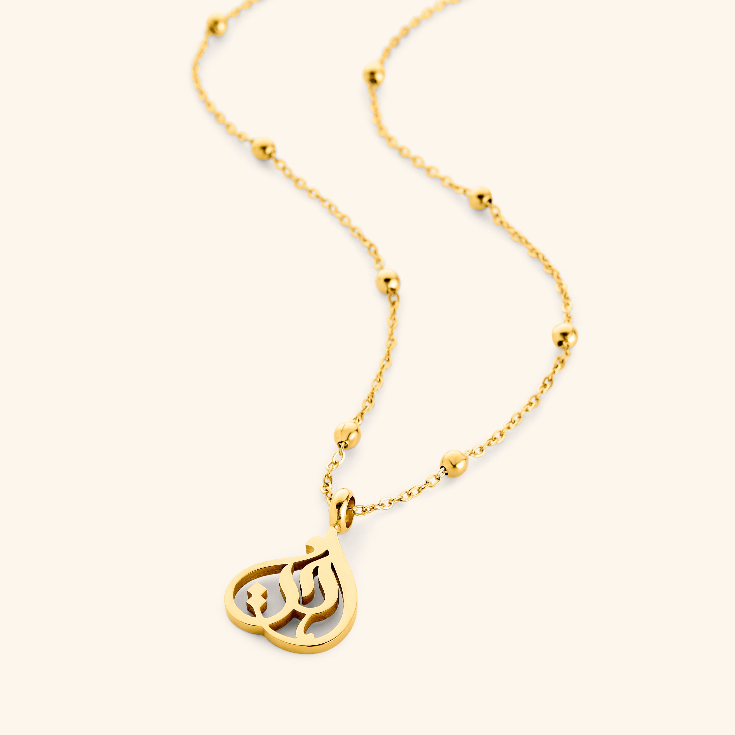 Close-up of Ukhti gold calligraphy pendant on velvet pouch – sister necklace