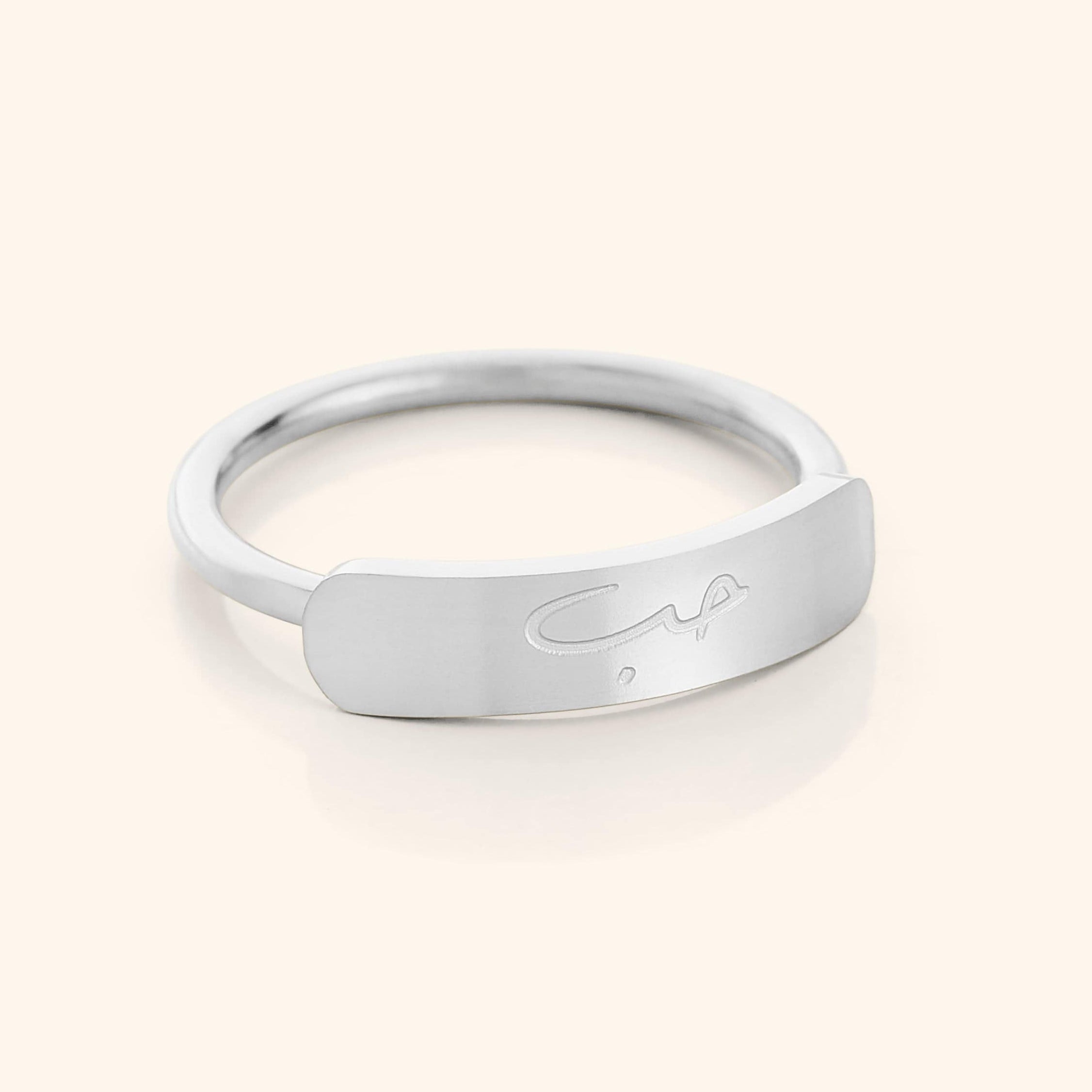 Lifestyle shot of the engraved ring worn alongside other minimalist jewelry pieces.