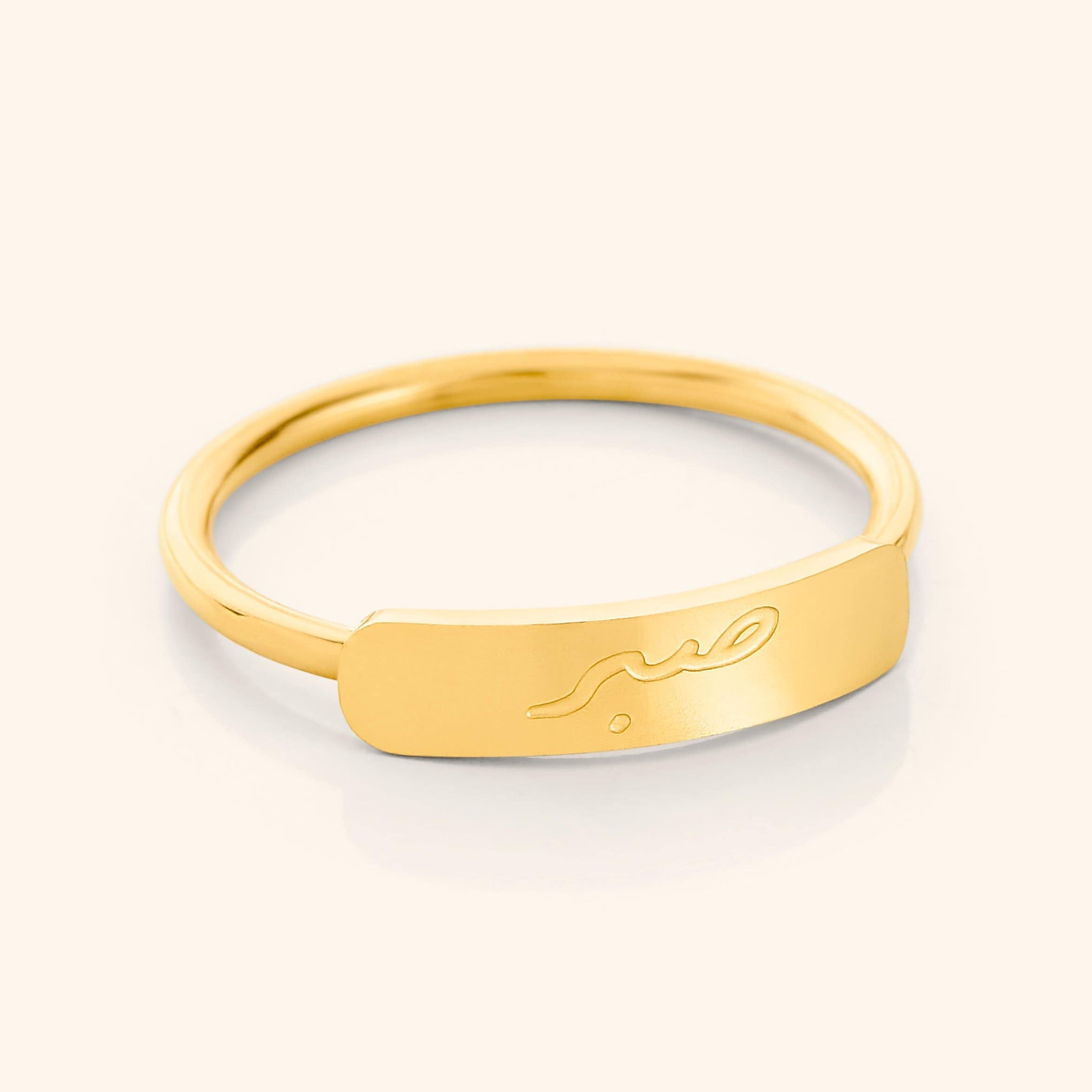 Close-up of the Patience Bar Ring highlighting the engraving and gold finish.