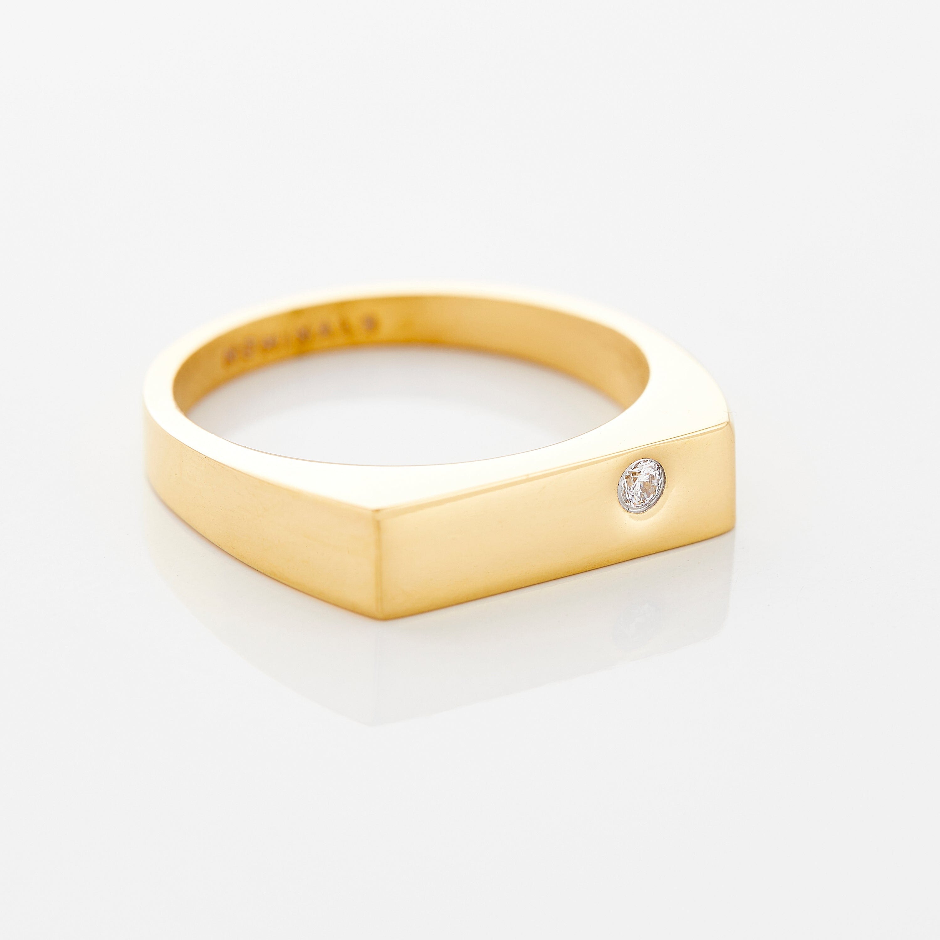 Close-up of GlimmerBar gold bezel ring with gemstone on velvet pouch