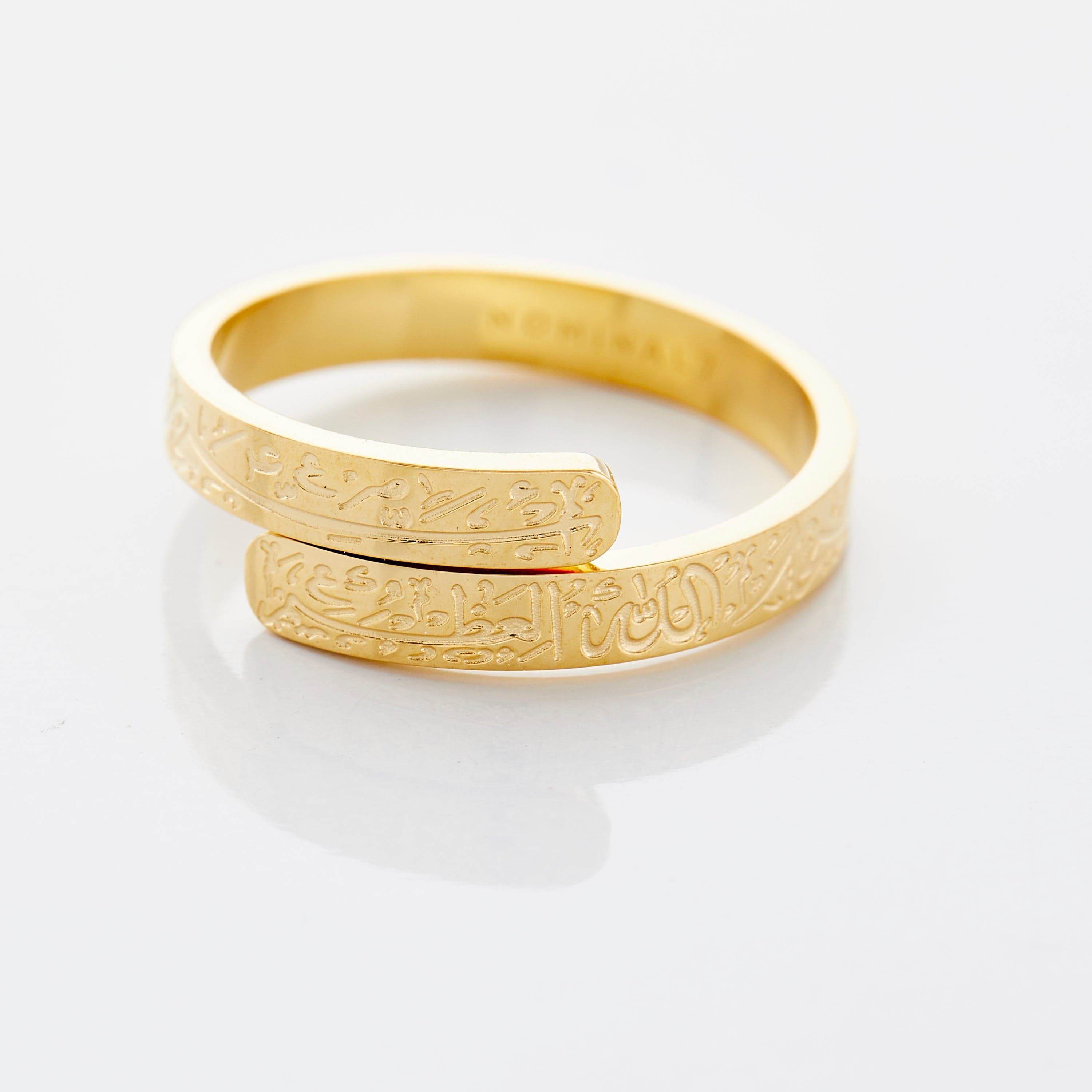Gold thikr wrap ring displayed on a soft velvet pouch, showcasing its elegant design.
