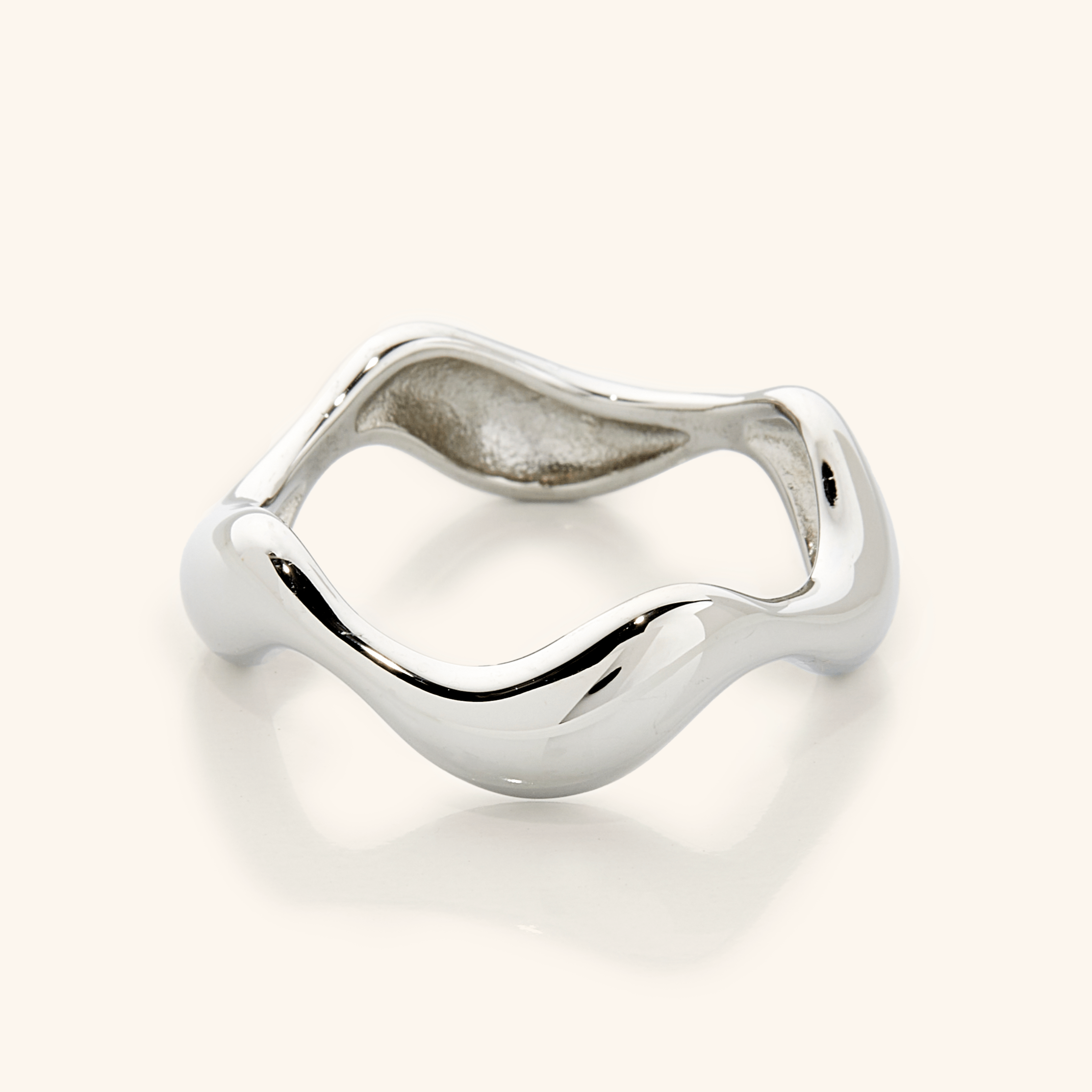 Oceanic Wave Gold Ring on a beach background, symbolizing its ocean-inspired theme.