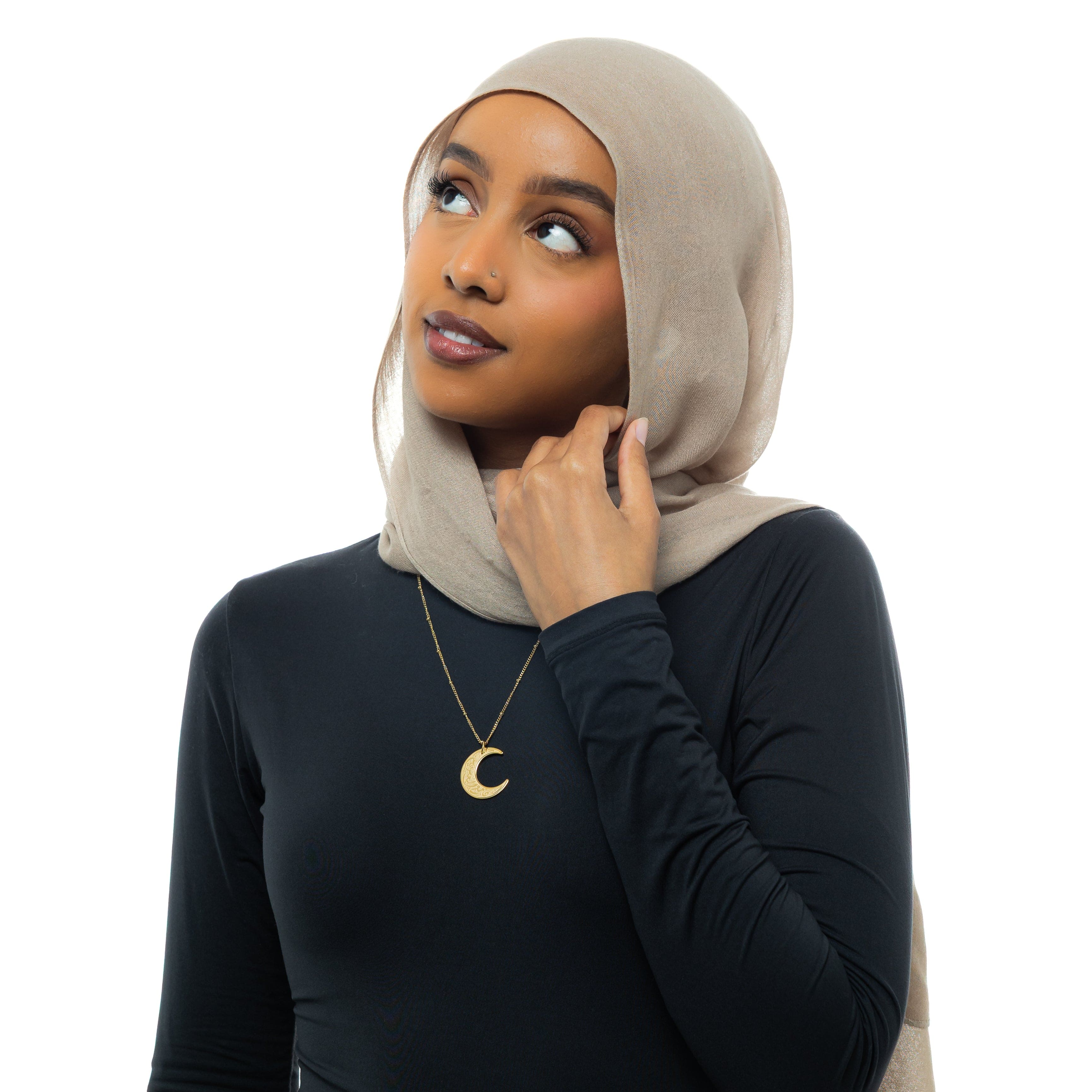 Crescent of Resilience Necklace worn by a model, highlighting its elegant design and Arabic calligraphy.