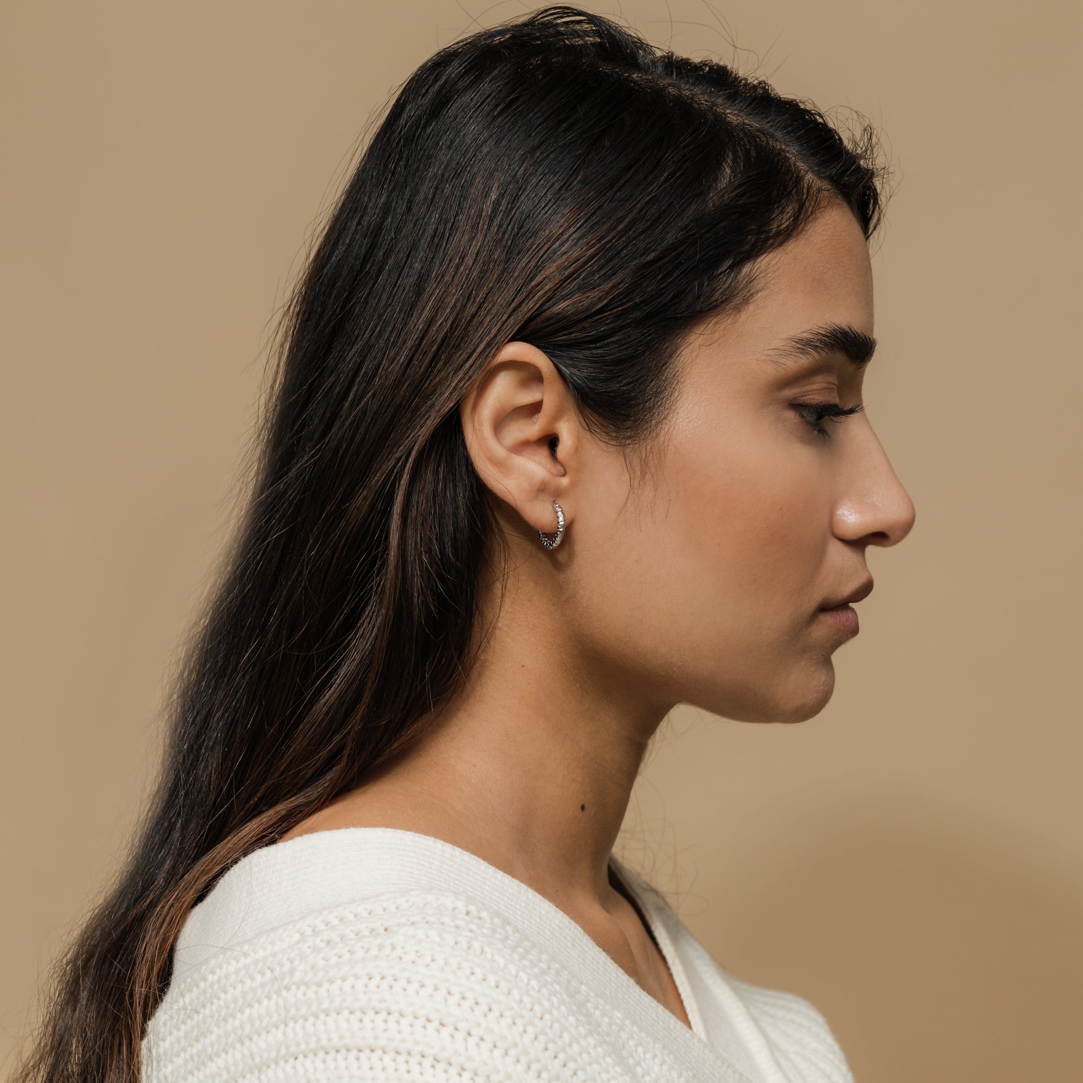 Mini gold hoop earrings for sensitive ears, showcasing the unique imperfect edges.