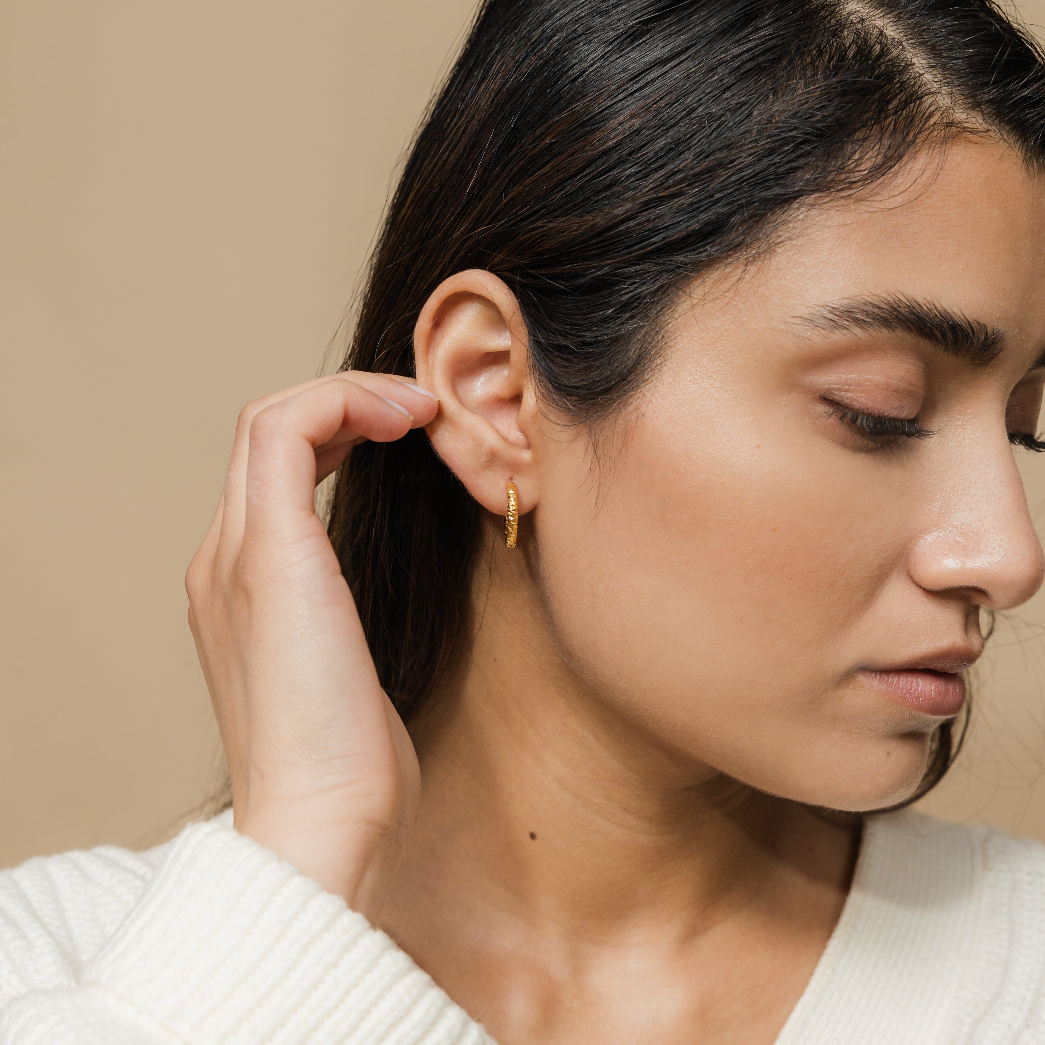 Close-up of waterproof hoop earrings, emphasizing the shiny gold finish.
