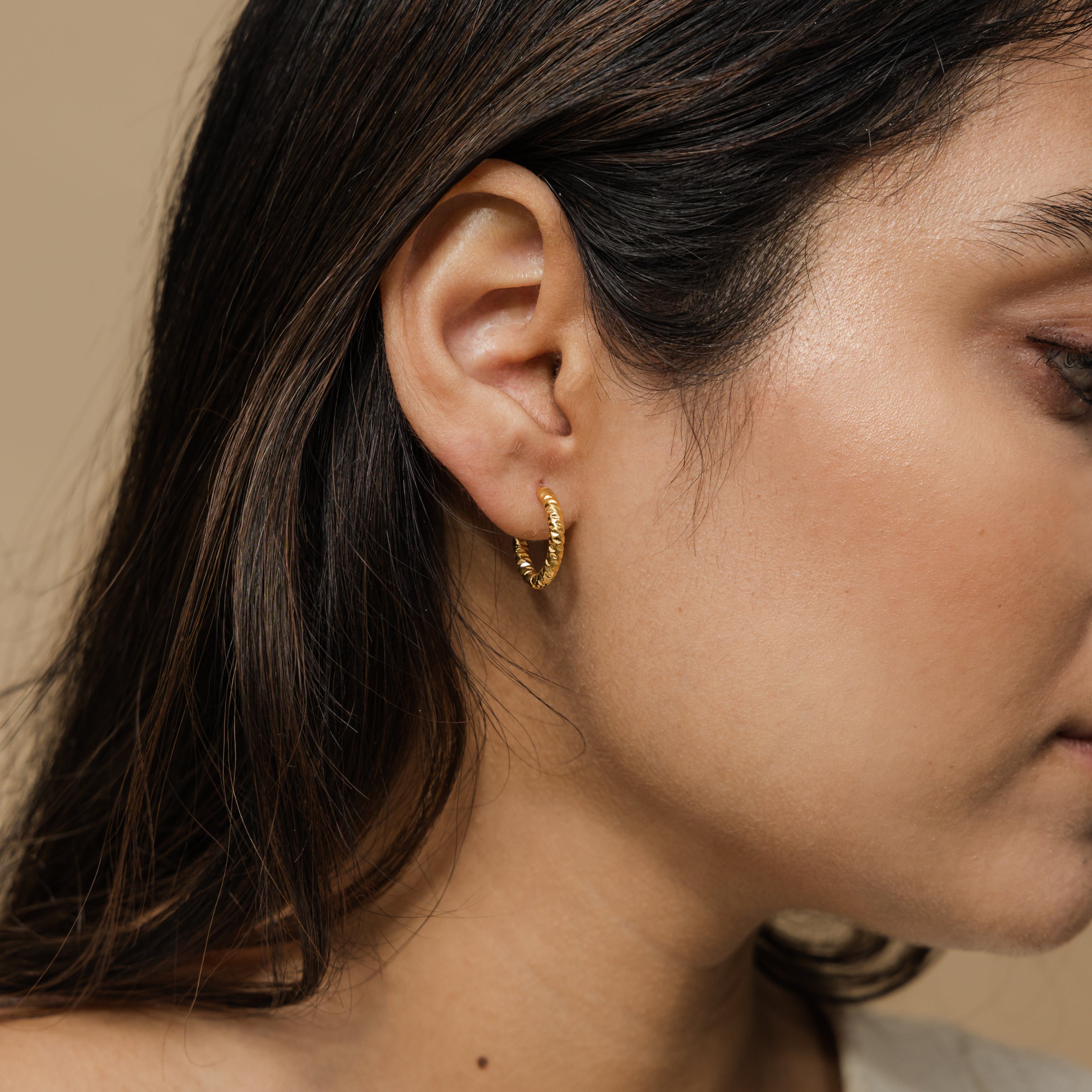Close-up of waterproof hoop earrings, emphasizing the shiny gold finish.