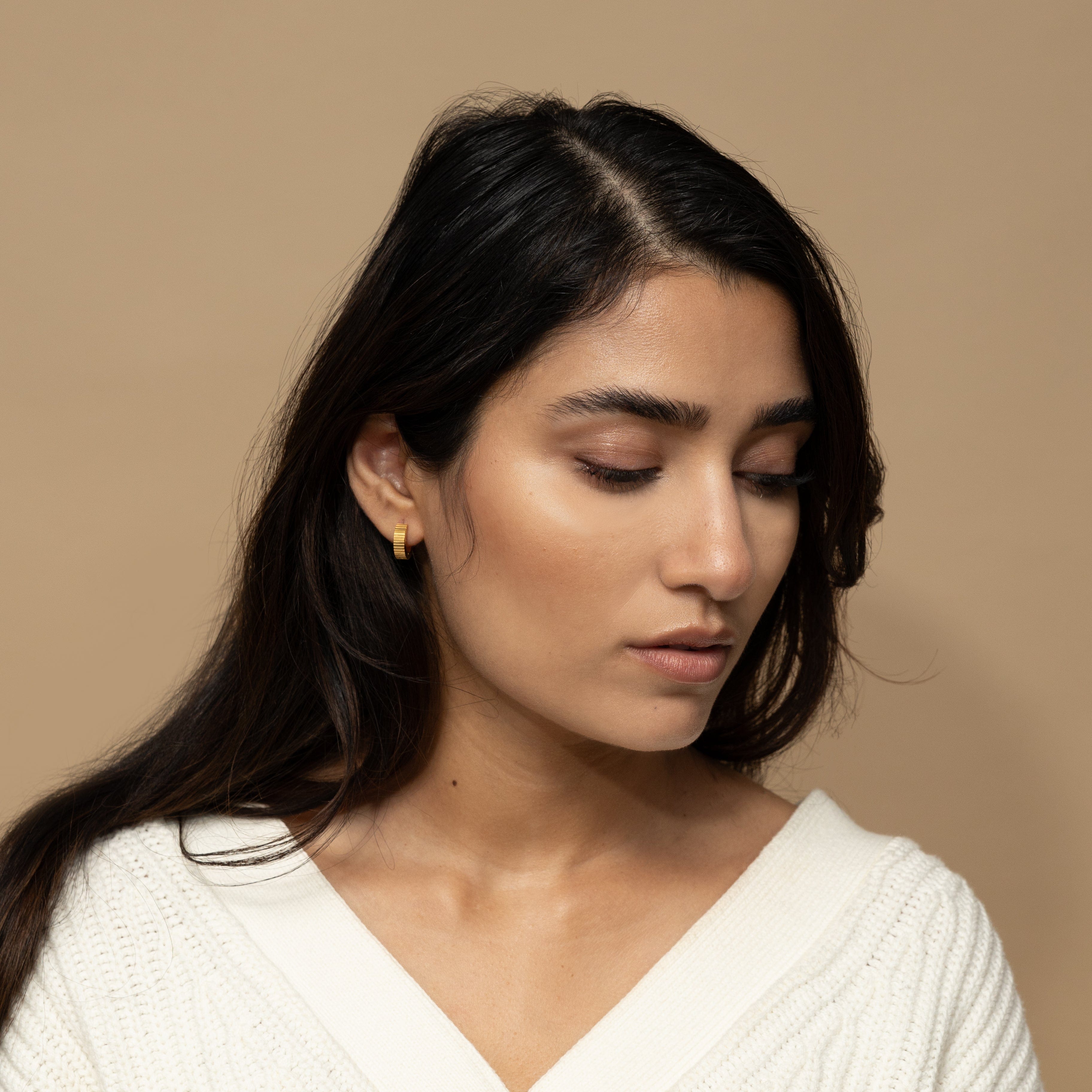 Elegant gold hoop earrings displayed in a velvet pouch, ideal for gifting.