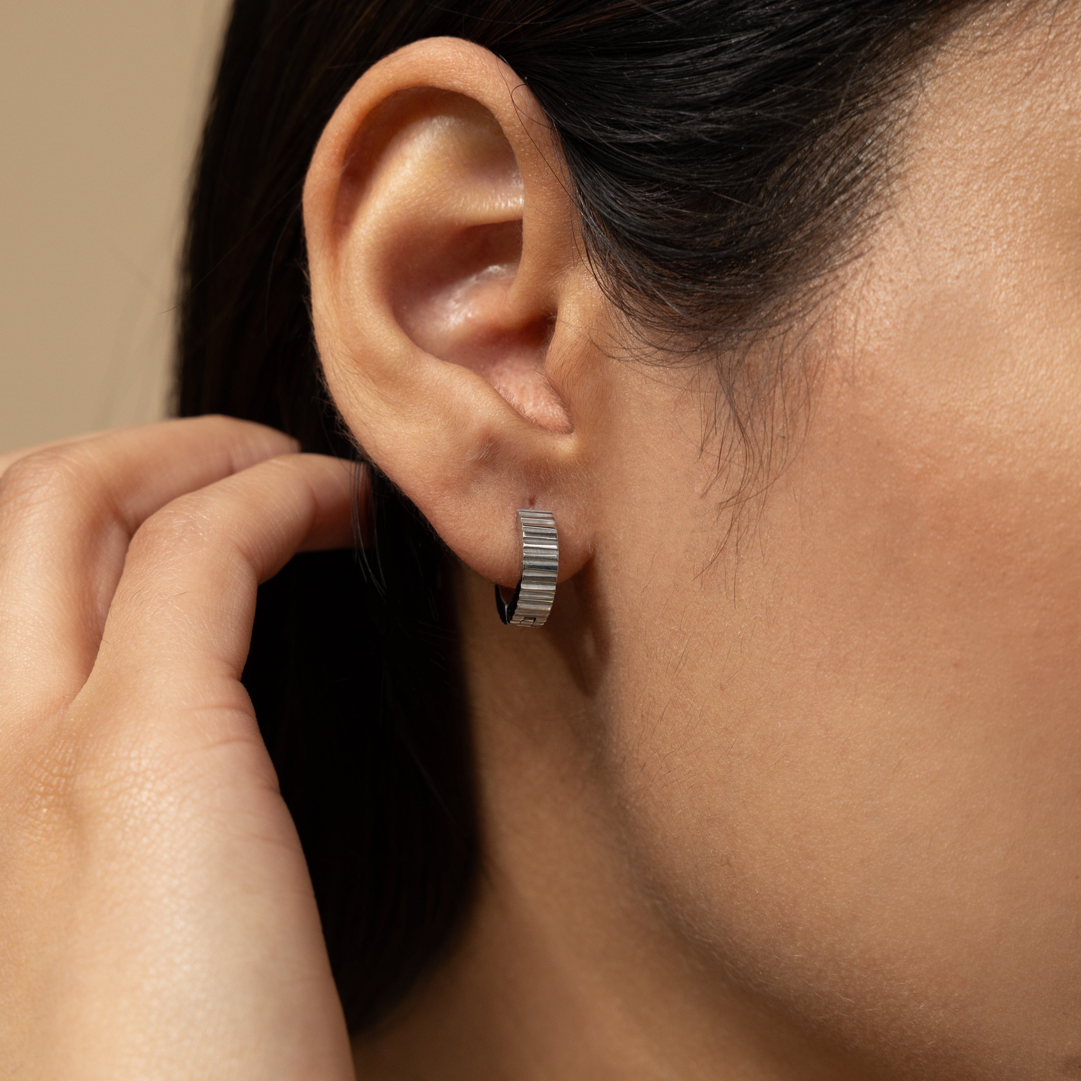 Elegant ridged gold hoop earrings on a model, showcasing a stylish look.