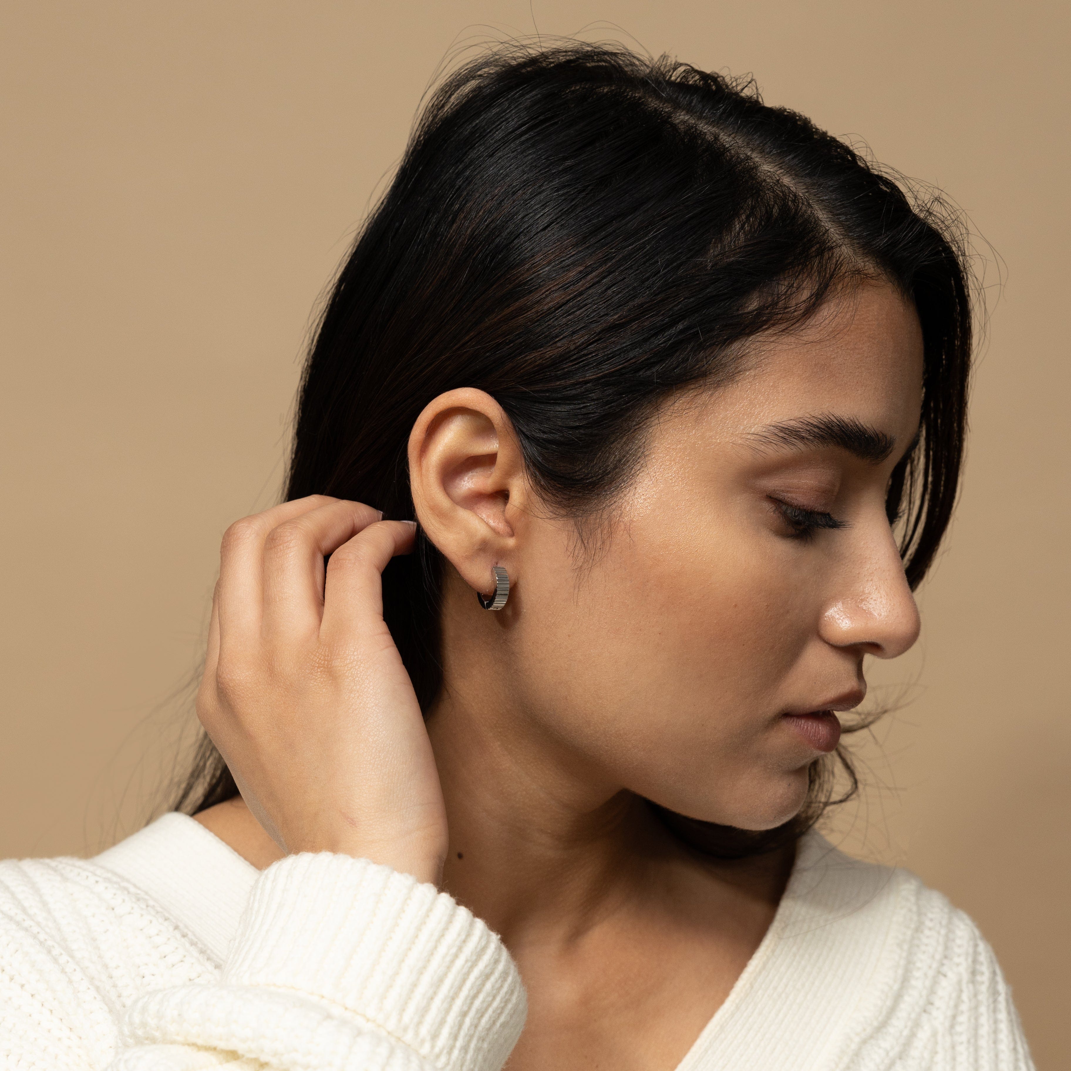 Close-up of small gold hoops with ridged design, highlighting quality craftsmanship.