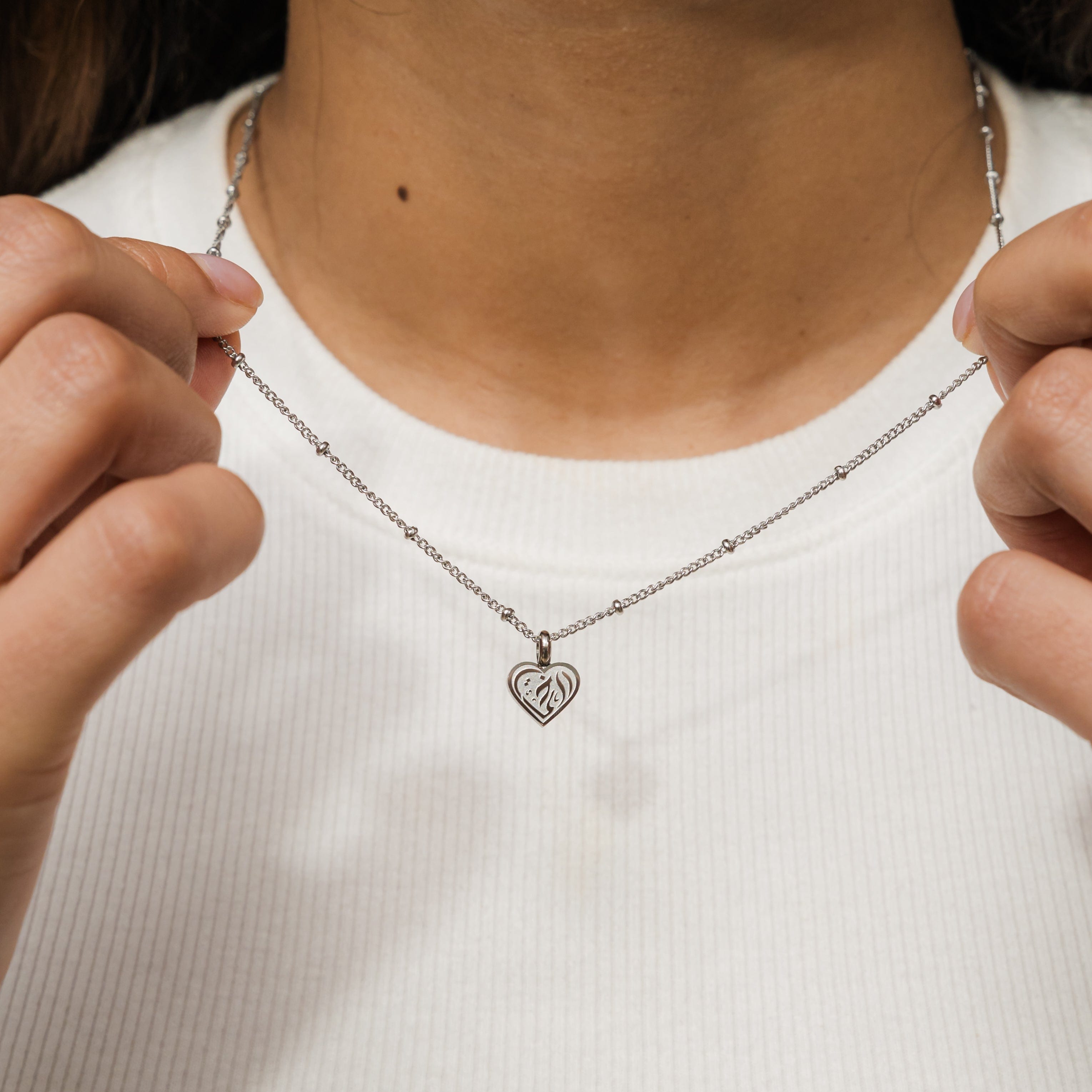 Close-up of sisterly love heart pendant necklace showcasing engraving in Arabic.