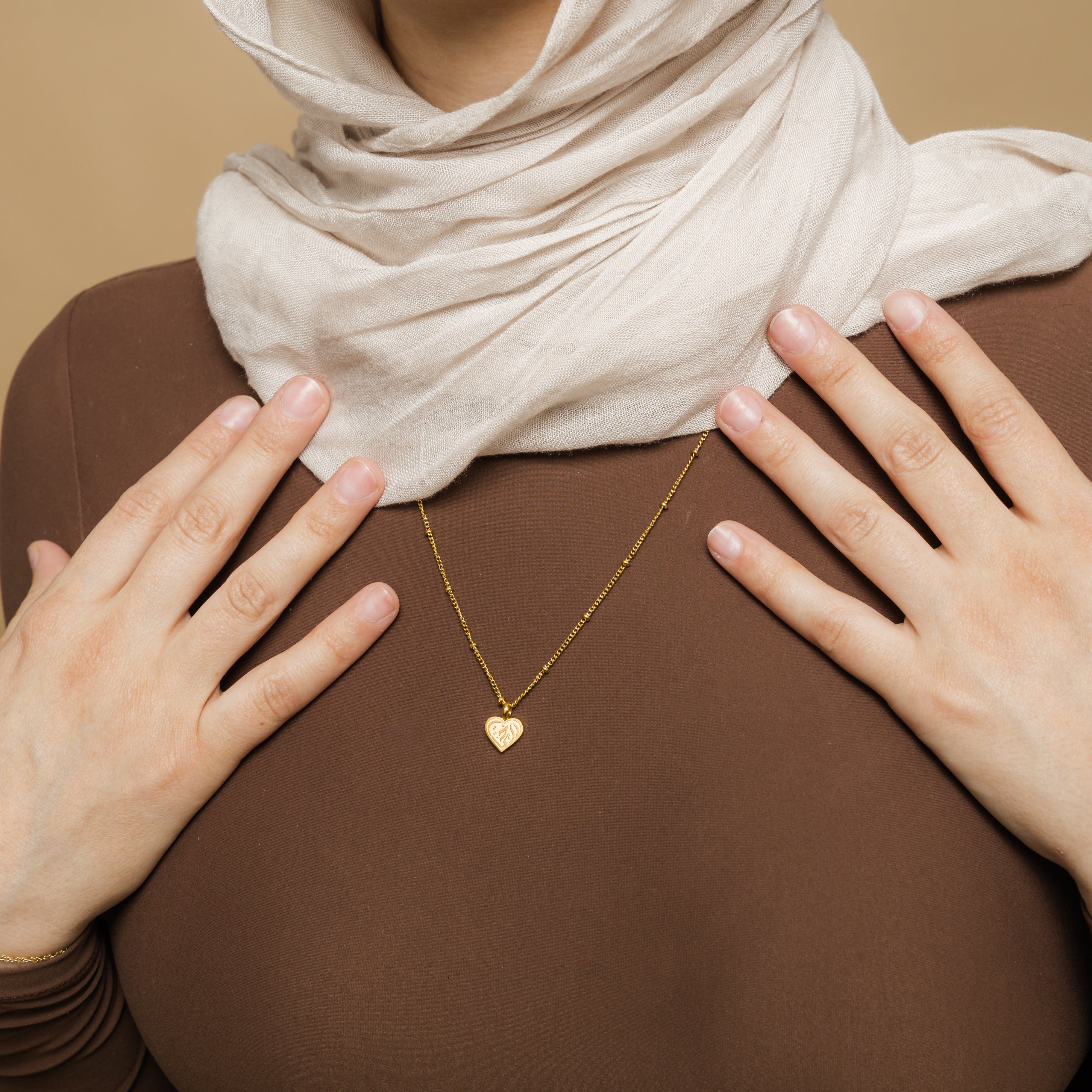 Close-up of sisterly love heart pendant necklace showcasing engraving in Arabic.