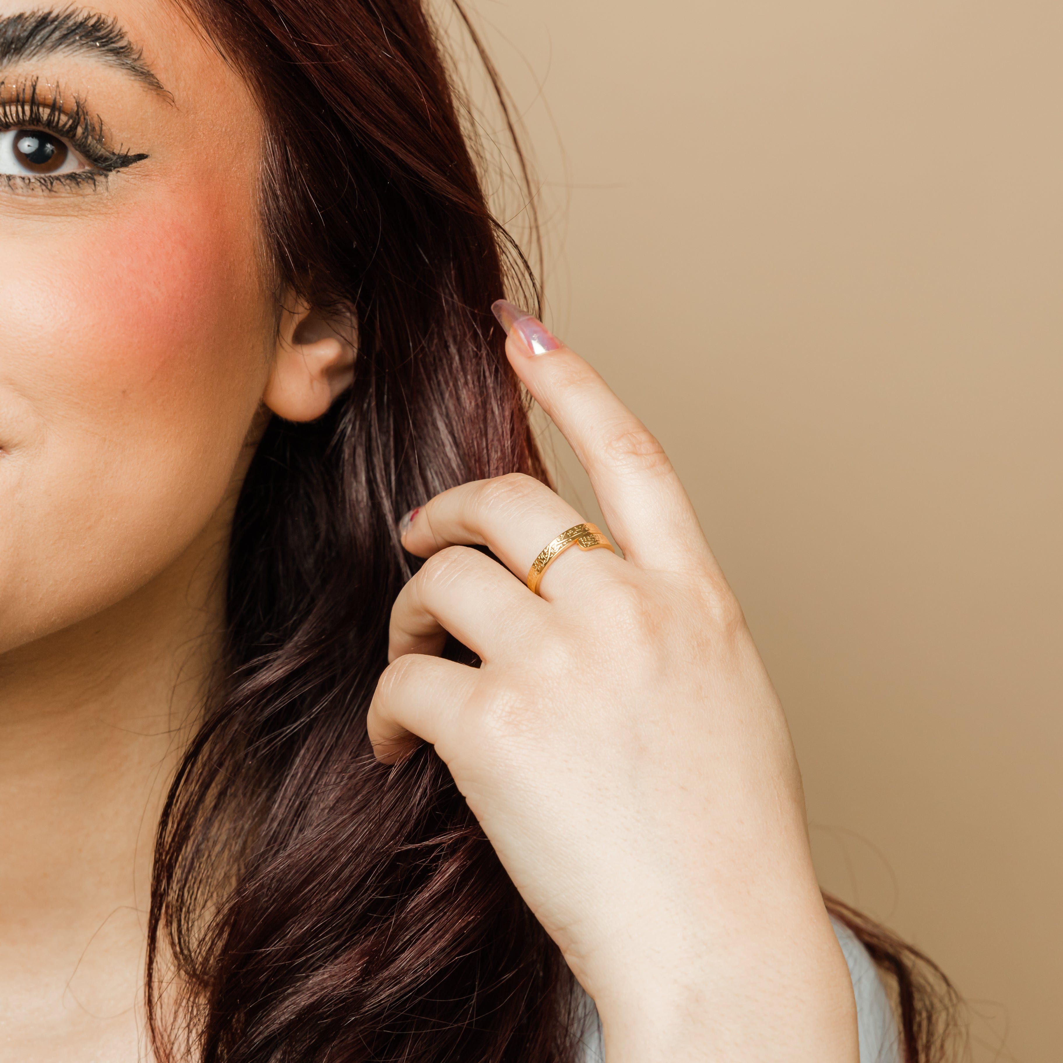 Gold thikr wrap ring displayed on a soft velvet pouch, showcasing its elegant design.