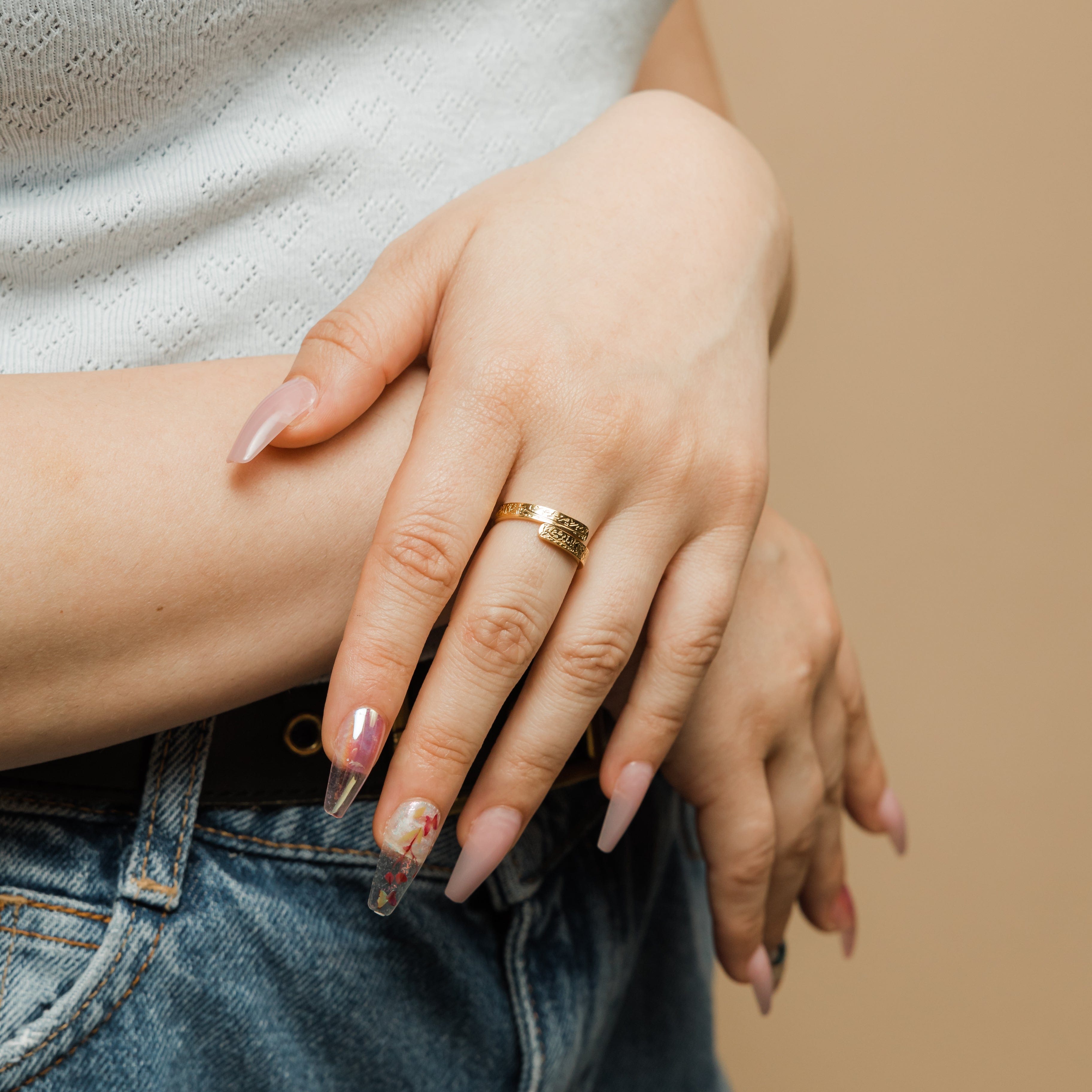 Close-up view of the engraved thikr phrase on the gold wrap ring, highlighting its intricate craftsmanship.
