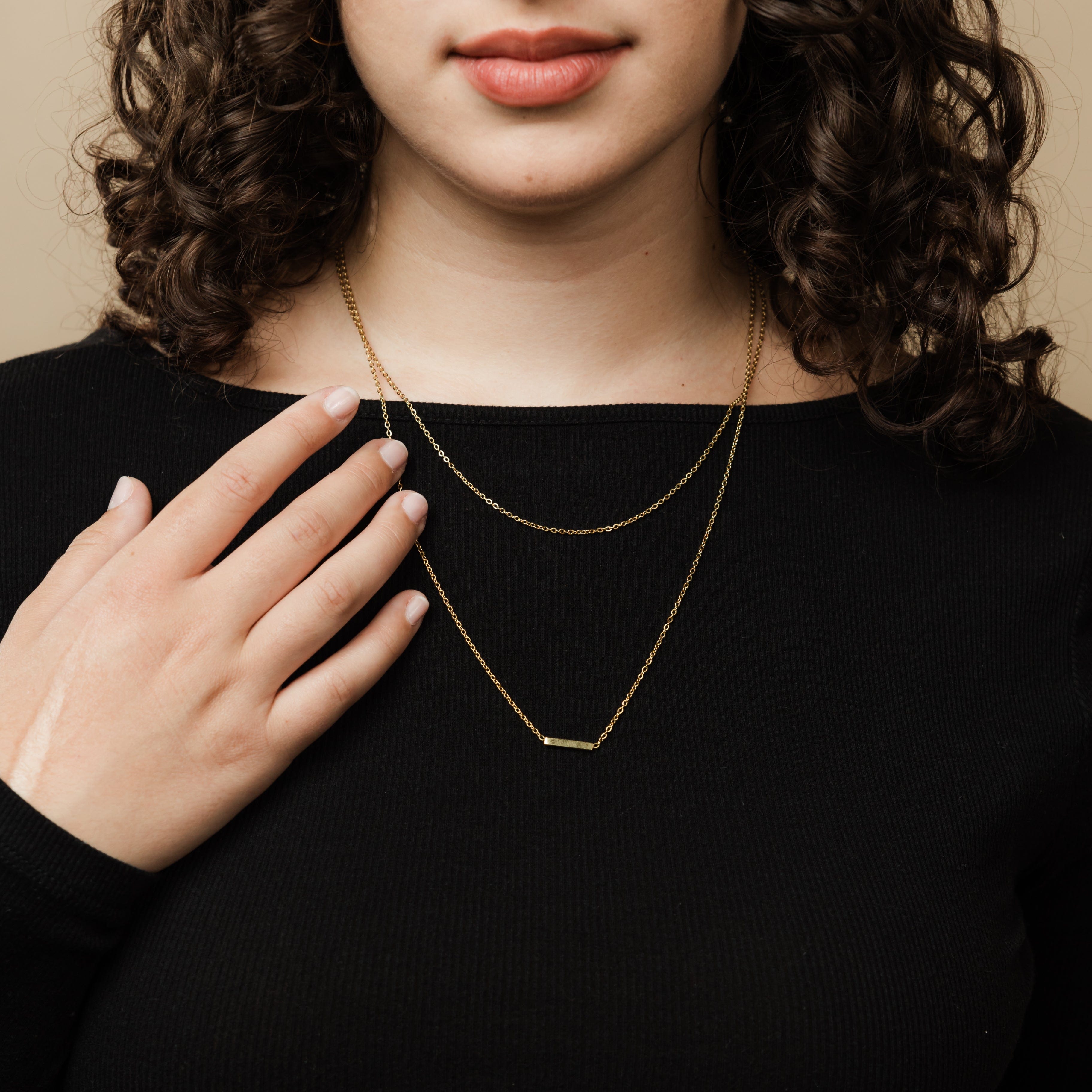 Close-up of the gold cable chain and bar necklace highlighting the quality and craftsmanship.