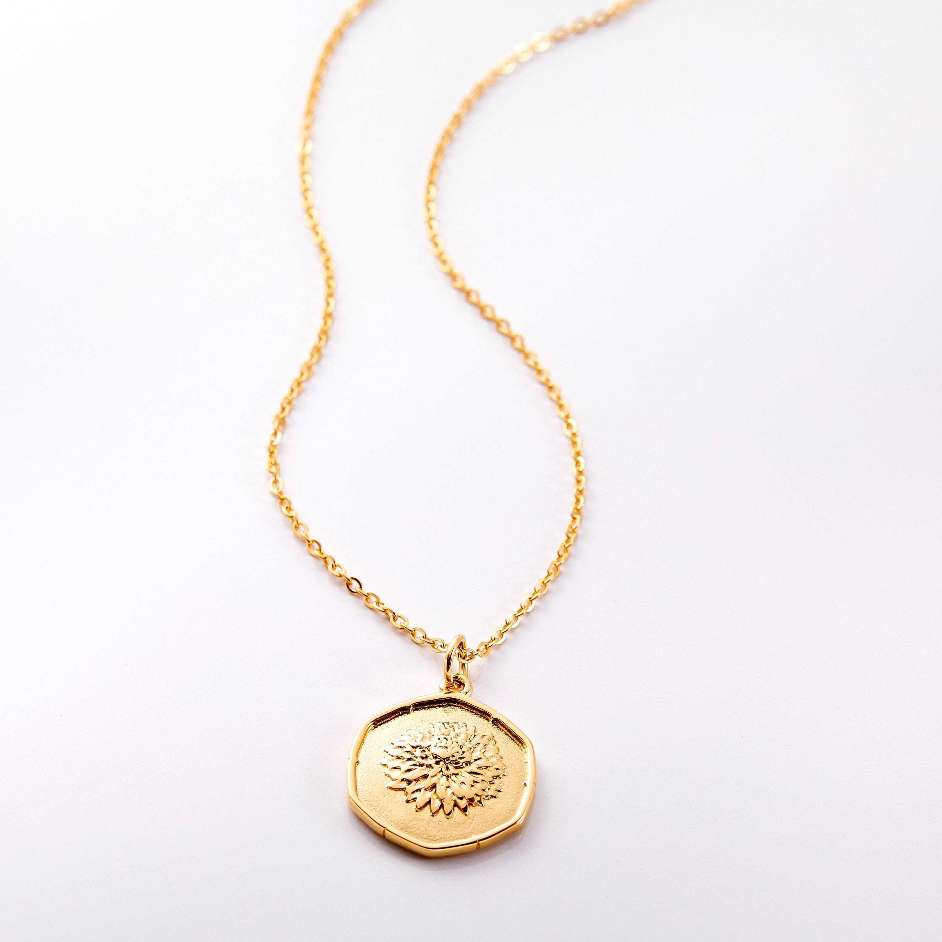 Aster Charm Necklace displayed on a wooden surface, highlighting its vintage-style design.