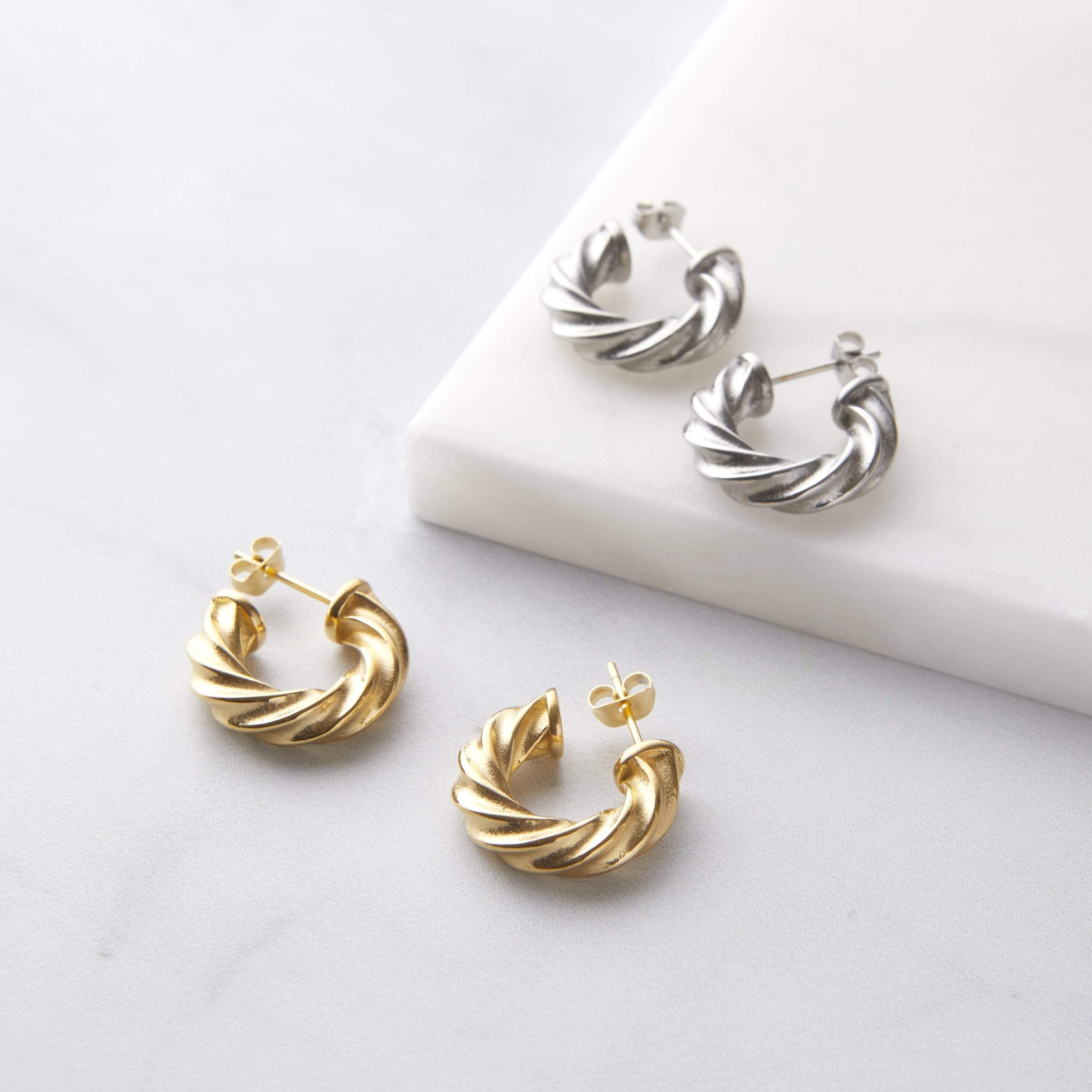 Close-up view of small gold braided hoop earrings showcasing the intricate design.