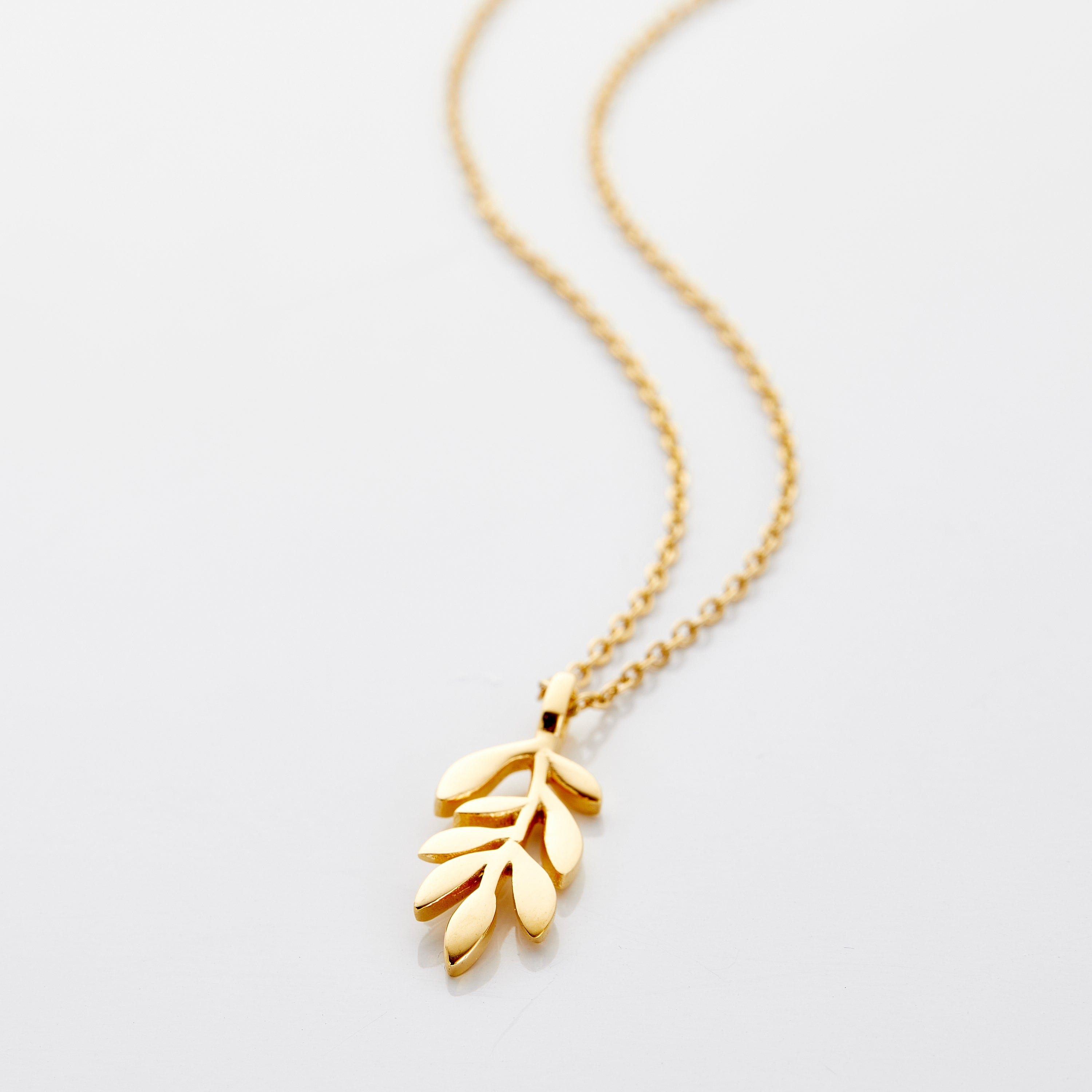 Close-up of the gold plated olive branch necklace highlighting its intricate details and shine.