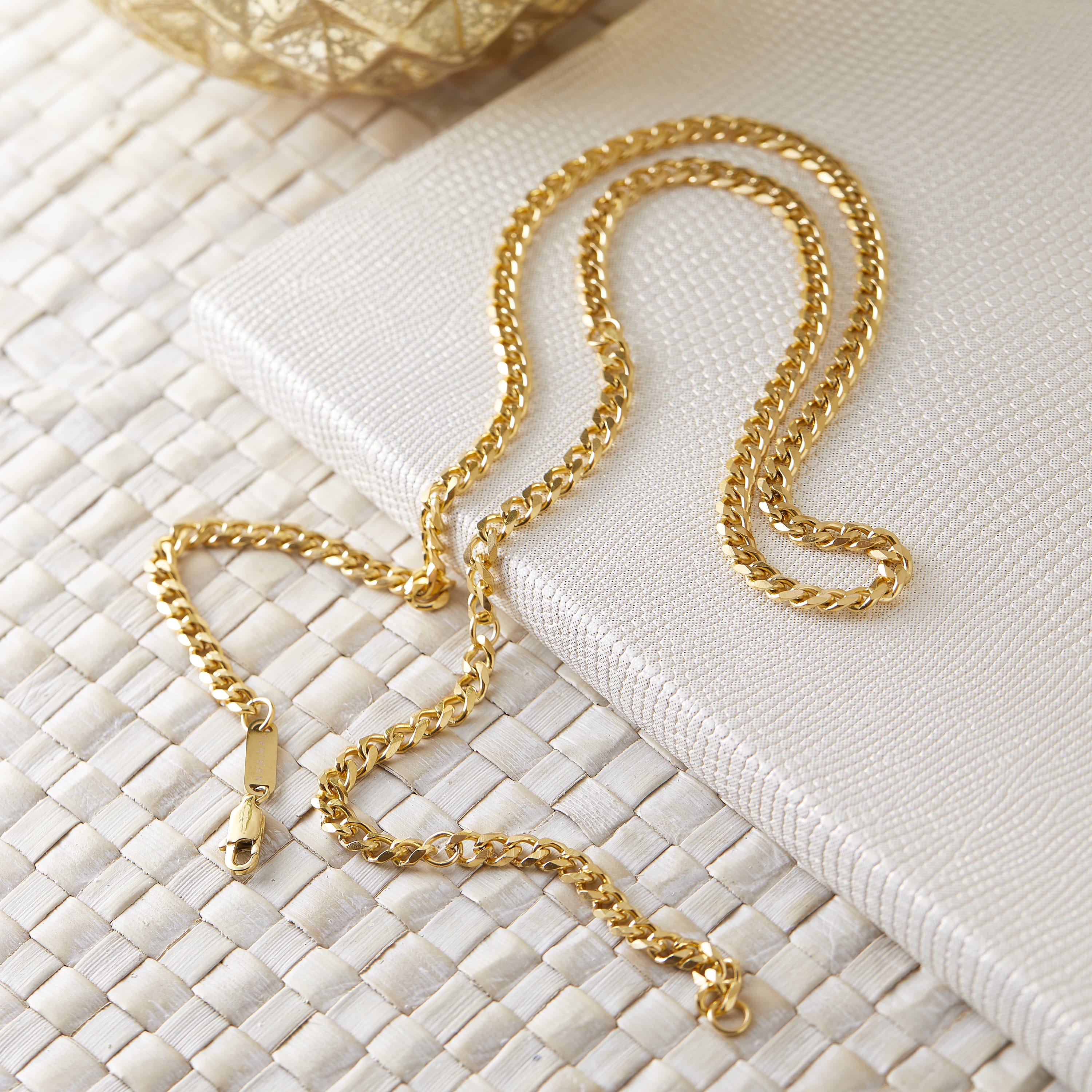 Close-up of the Cuban chain necklace highlighting its oval links and gold finish.