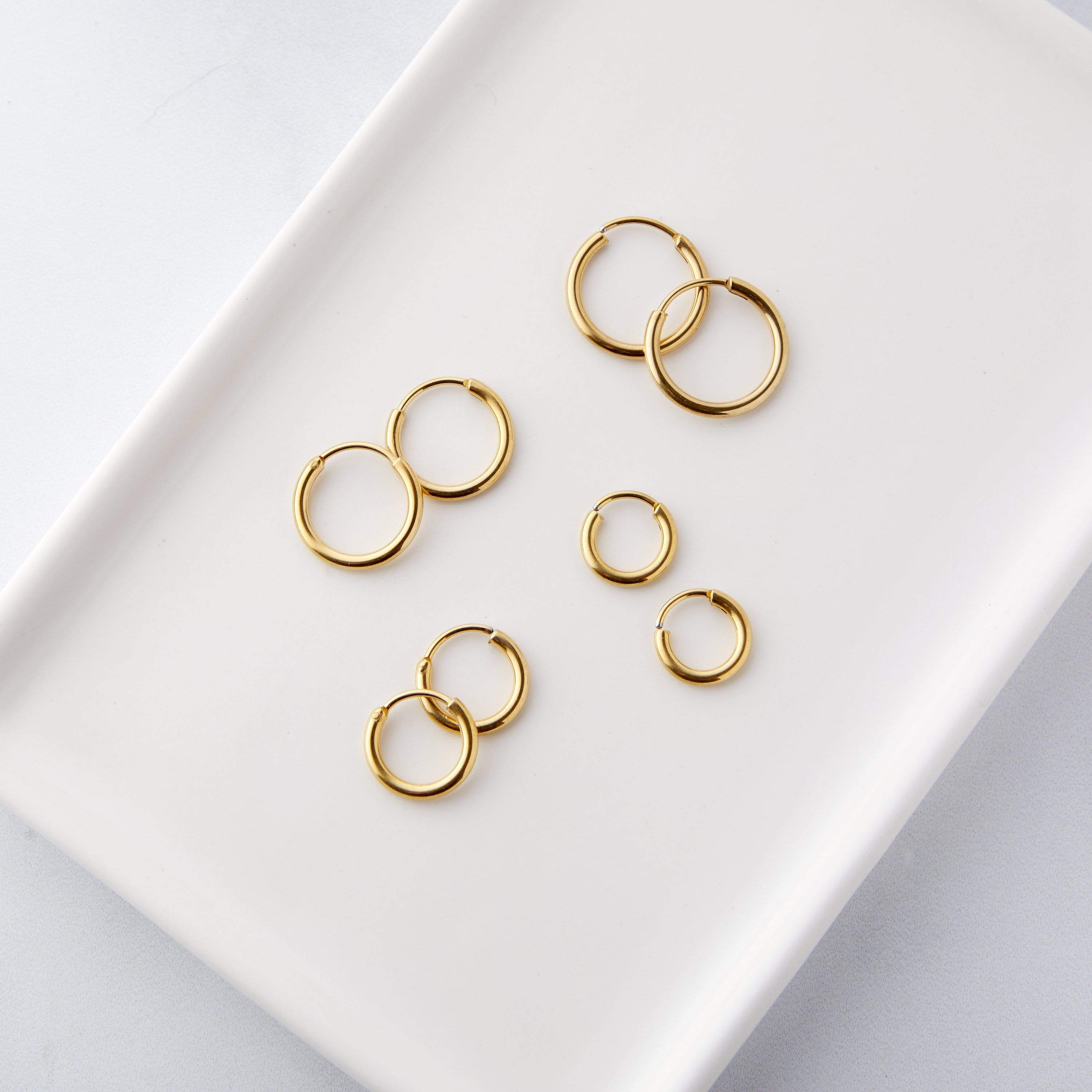 Close-up of the essential mini hoop earrings set displaying the four different sizes in a velvet pouch.