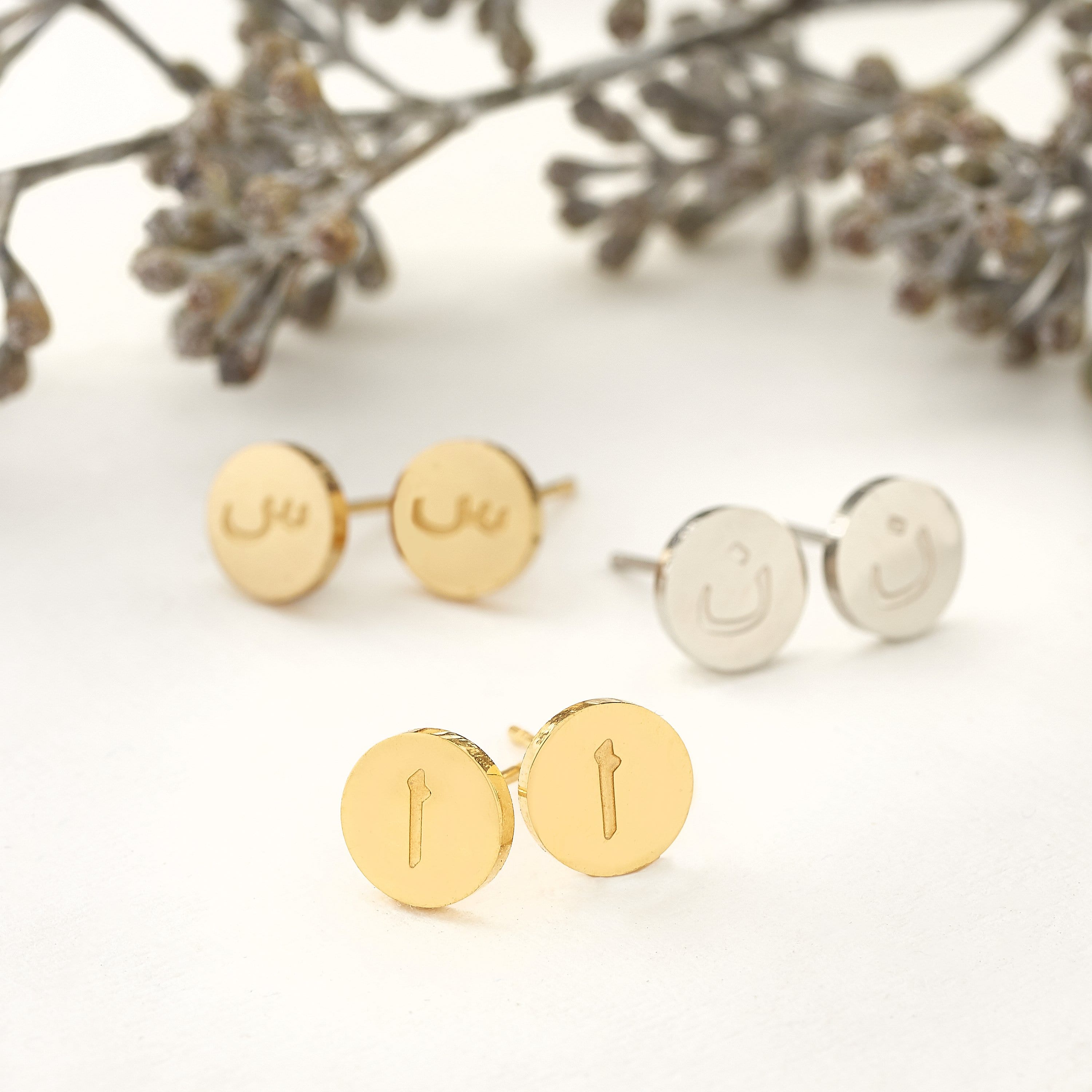 Close-up view of personalized Arabic letter earrings showcasing their gold finish and intricate design.
