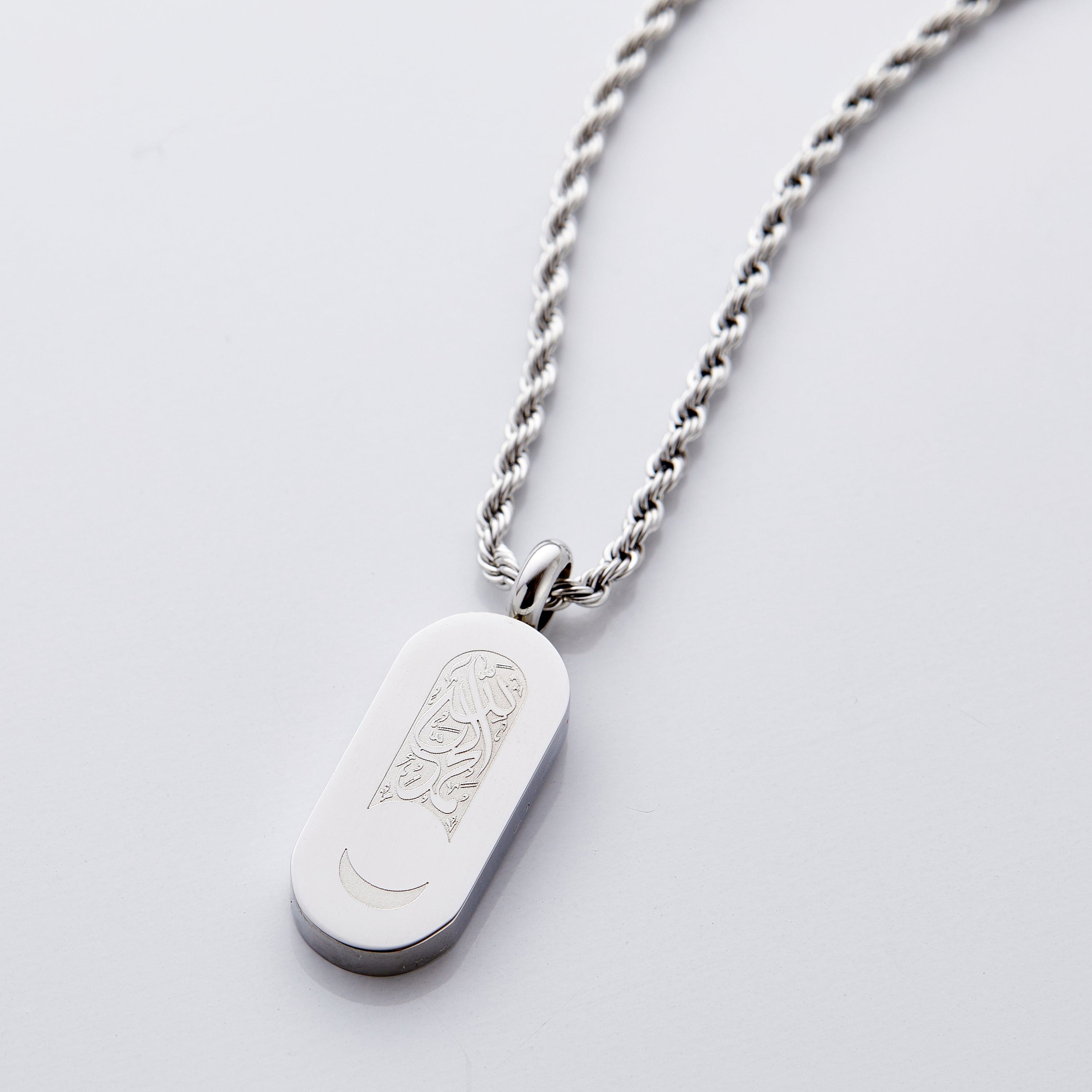Close-up of men's jewelry with Arabic calligraphy and crescent moon cutout