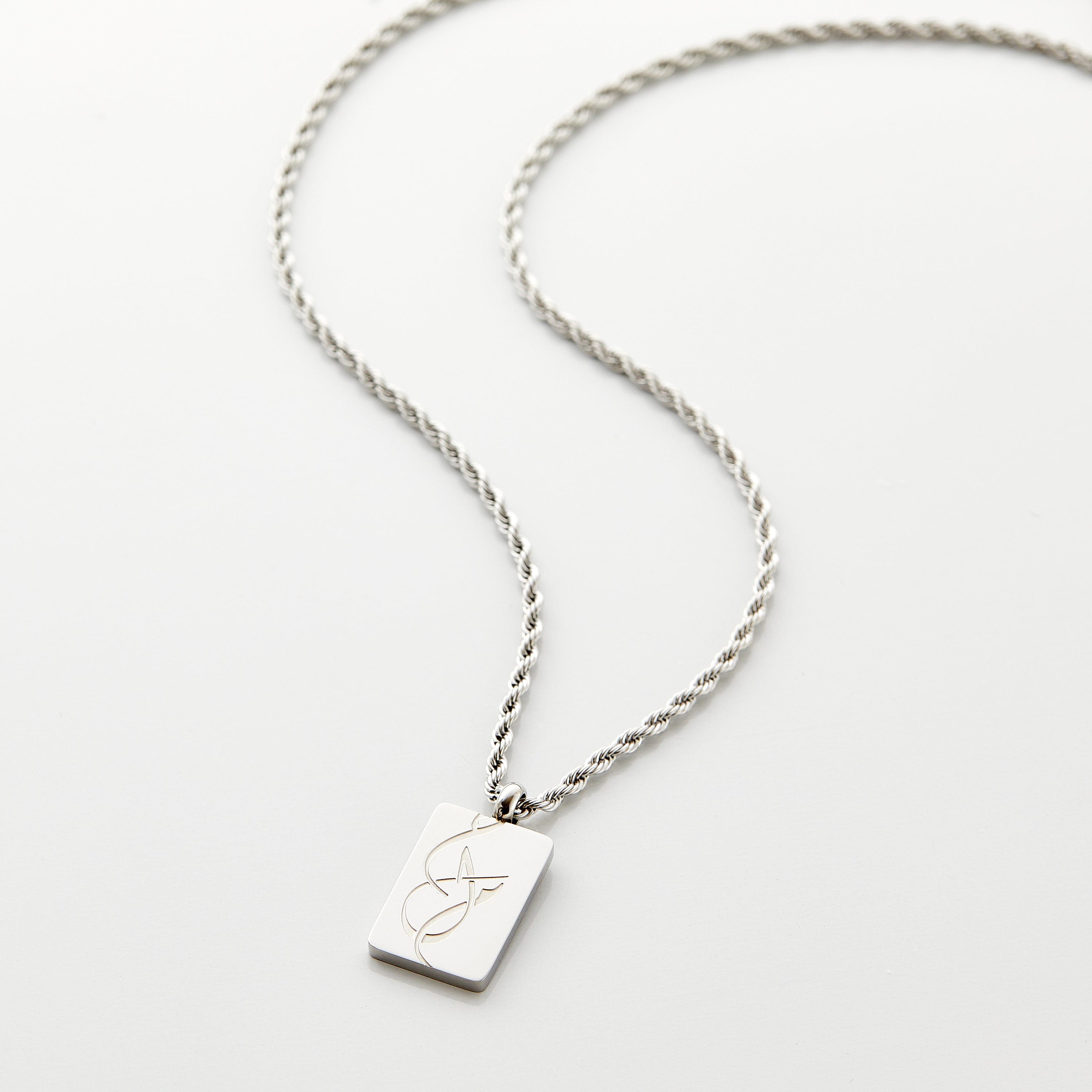 Dream Arabic Calligraphy Necklace displayed on a wooden surface, highlighting its elegant pendant.
