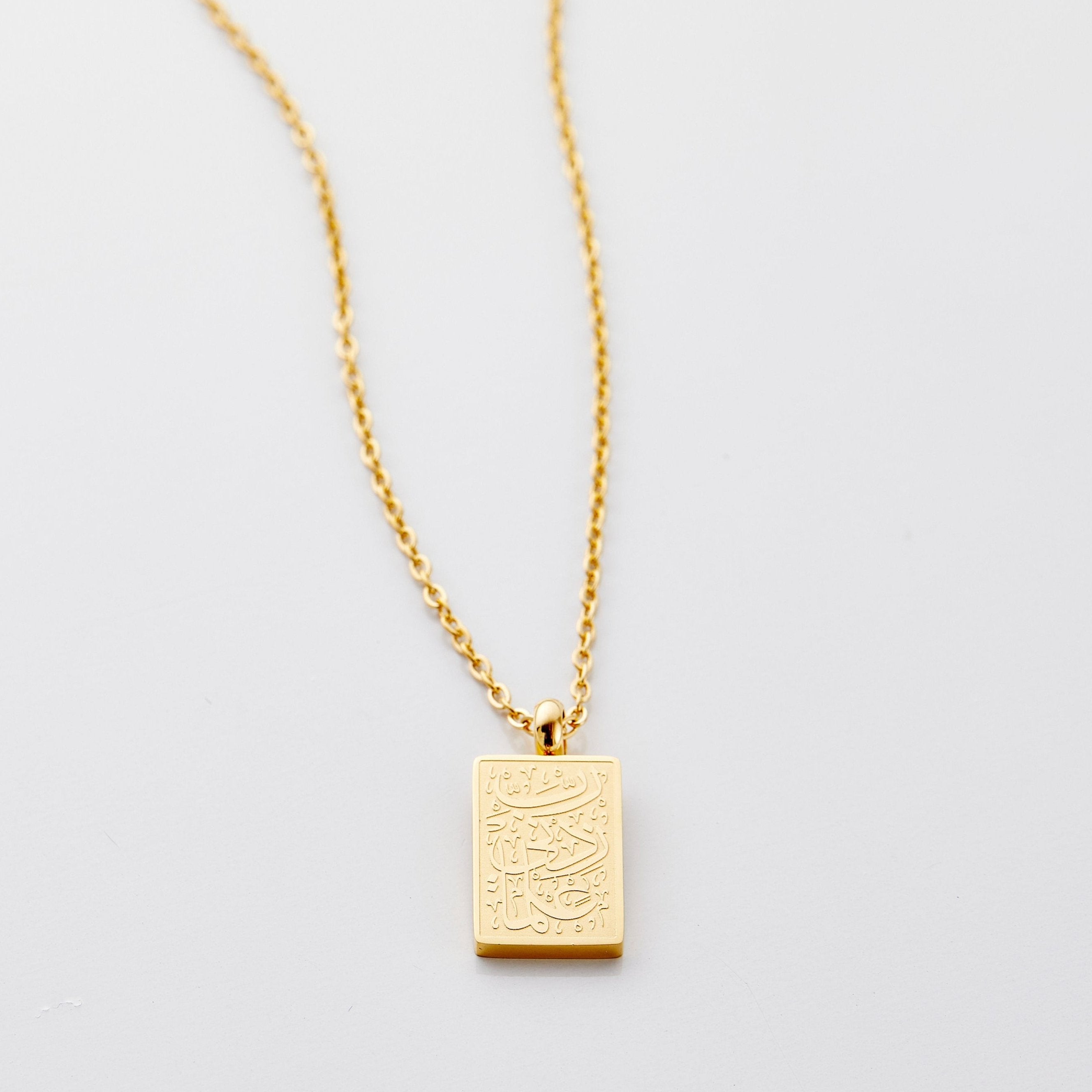Close-up of the engraved necklace showcasing Arabic calligraphy.