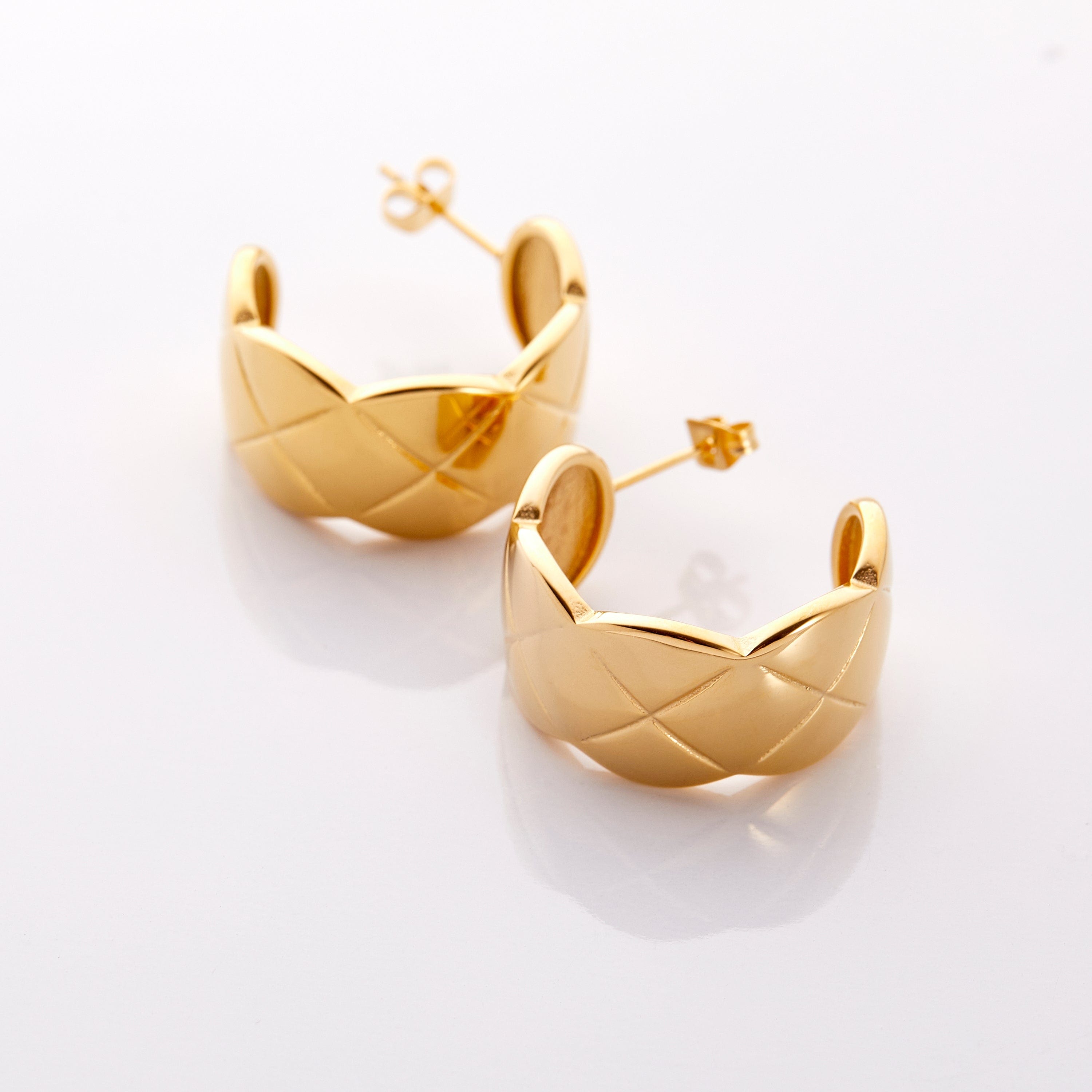 Close-up of the luxurious quilted hoop earrings showcasing the gold plating and design.