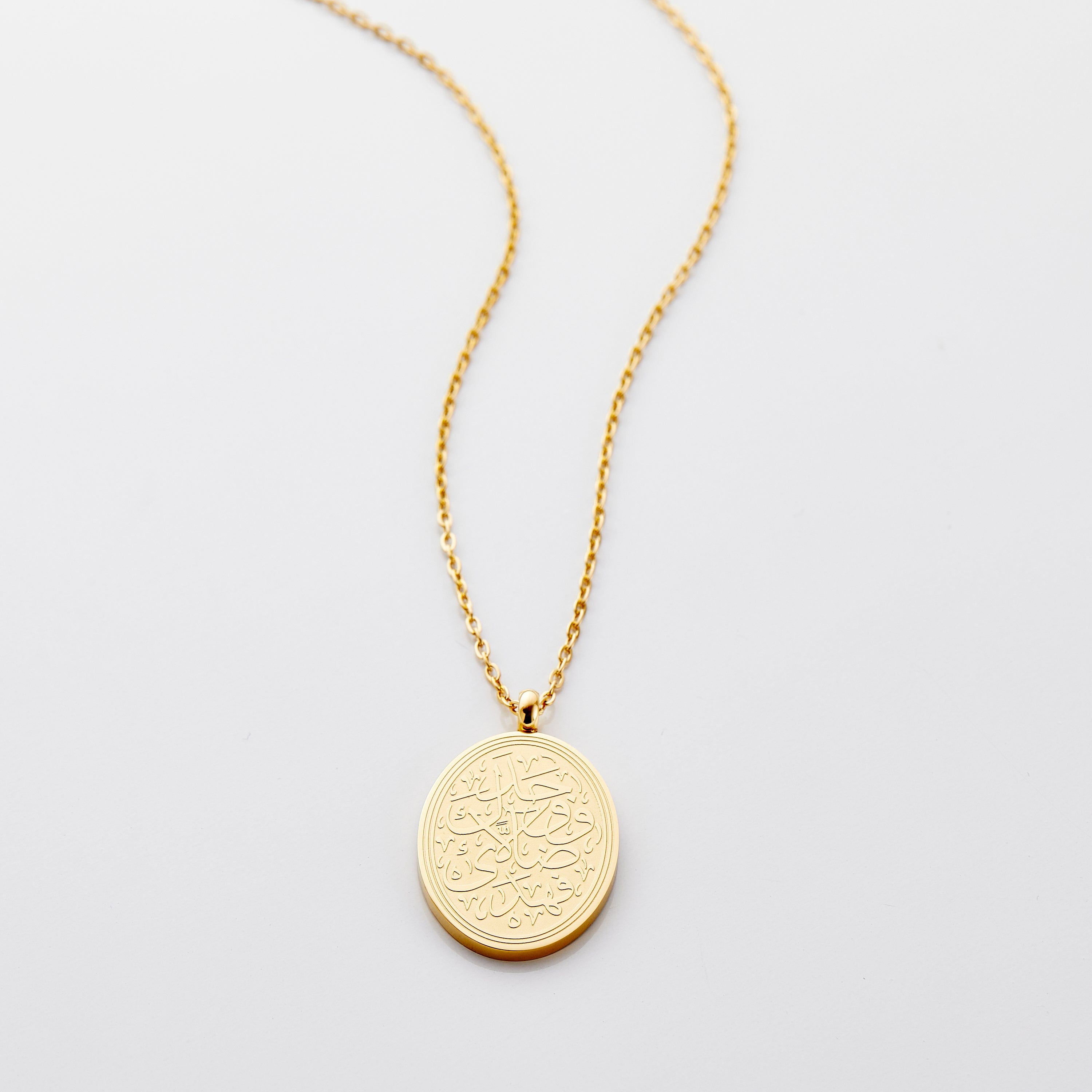 Close-up view of the Guided by Faith Quran verse necklace showcasing its intricate calligraphy and gold finish.